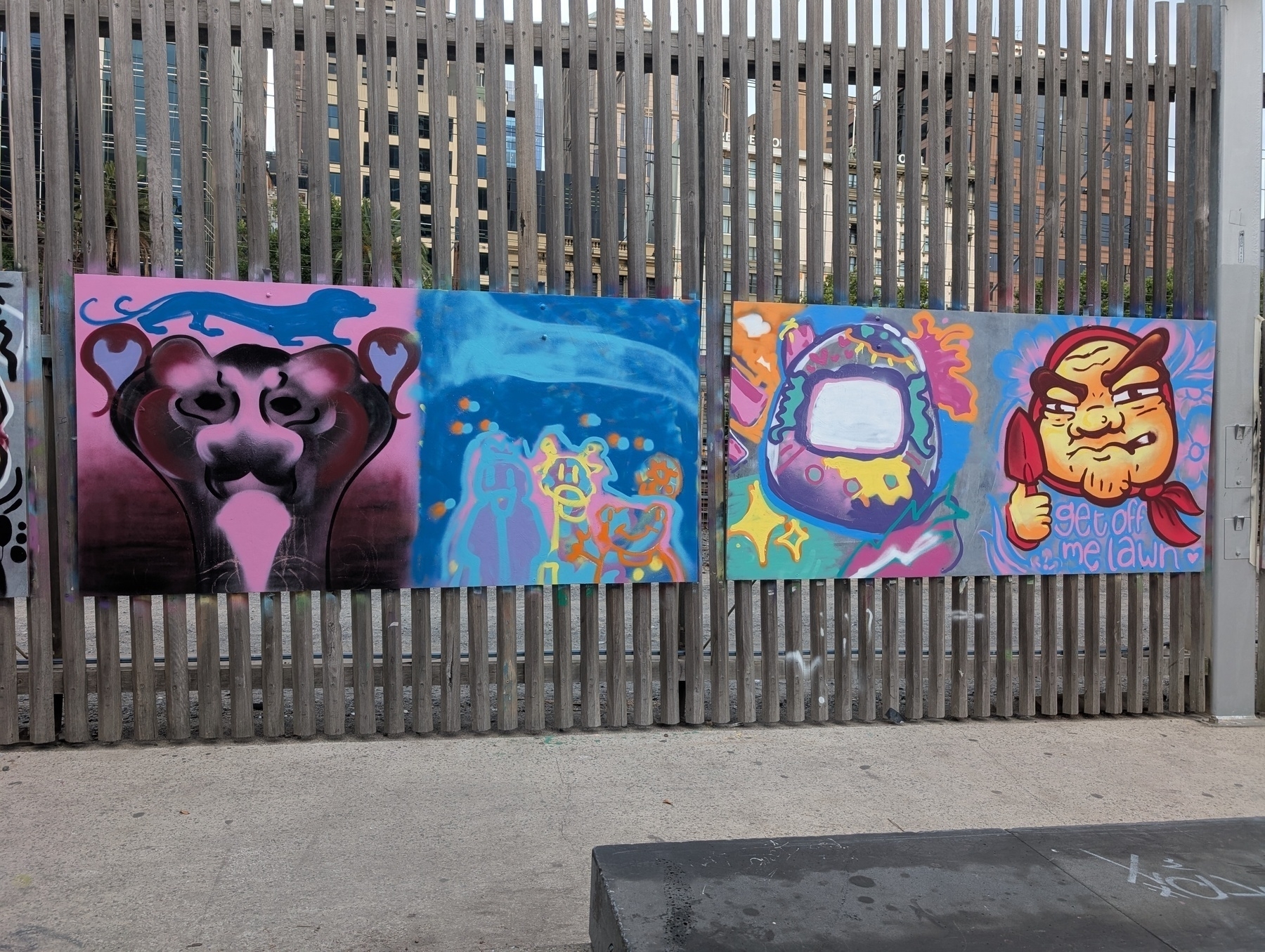 Auto-generated description: Graffiti art on a wooden fence features abstract designs and cartoonish characters.