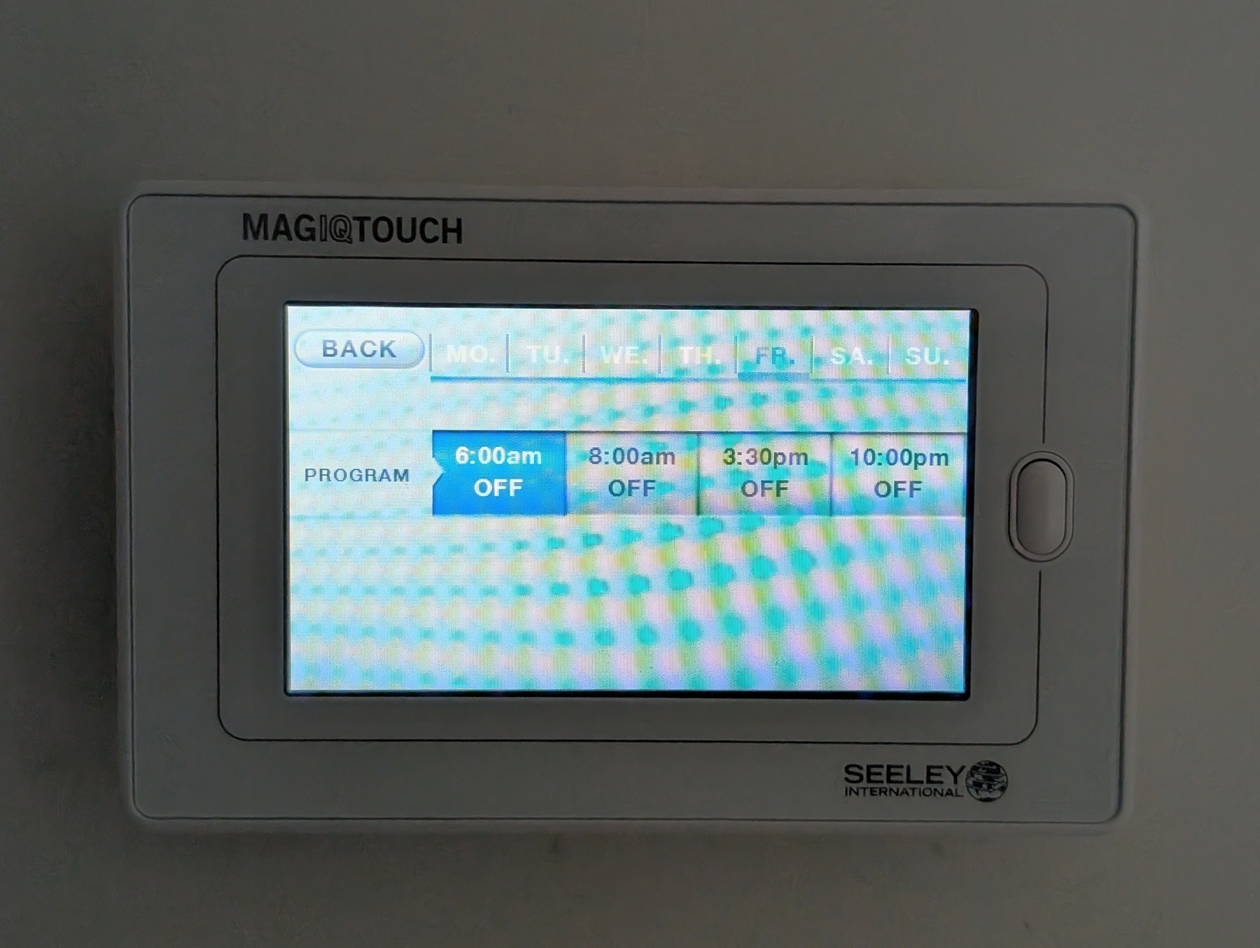 Auto-generated description: A digital control panel for a Seeley International air conditioning system displays a program schedule with times and statuses.