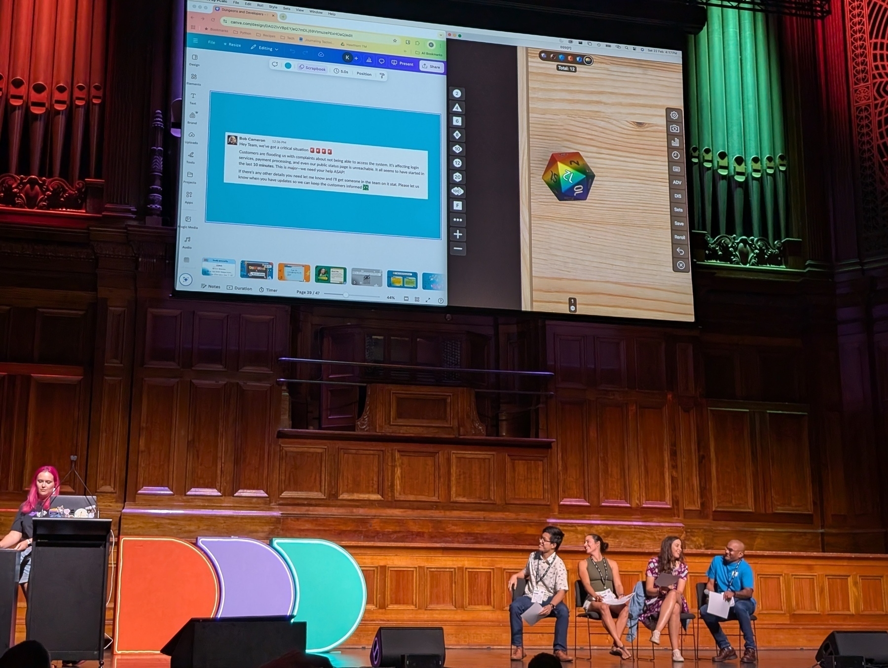 Auto-generated description: Four people are sitting on a stage with a large screen behind them displaying a web page and a wooden surface with a geometric object.