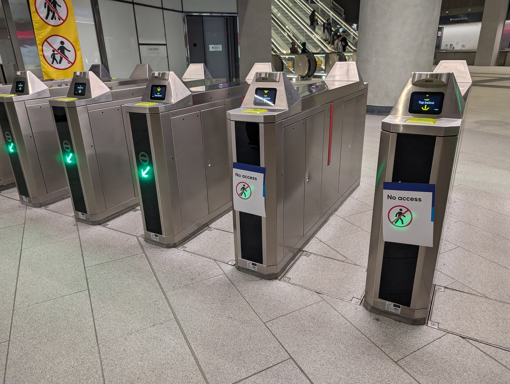 A row of metro turnstiles includes a few with No access signs and visible green entry indicators.