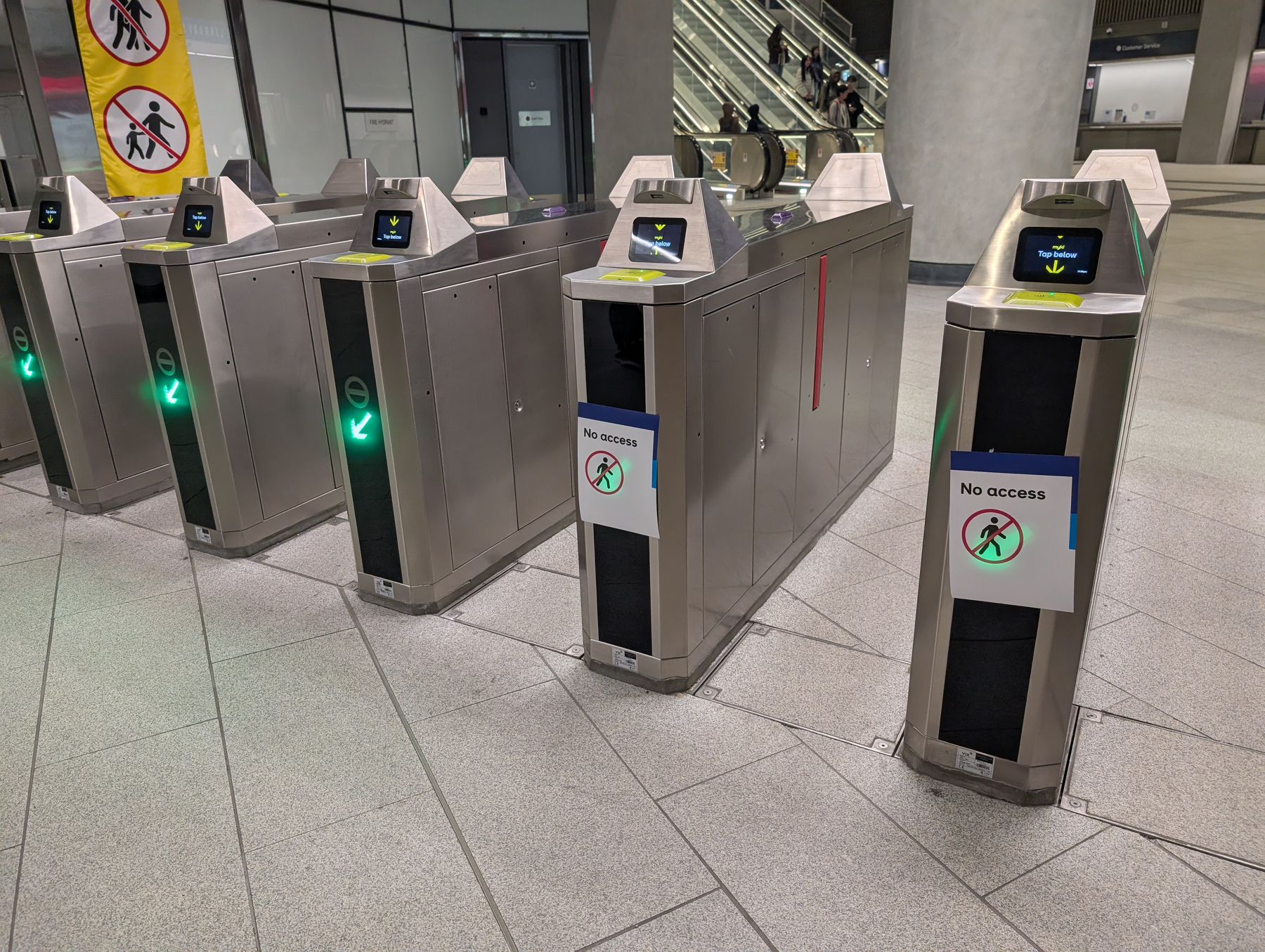 A row of metro turnstiles includes a few with No access signs and visible green entry indicators.