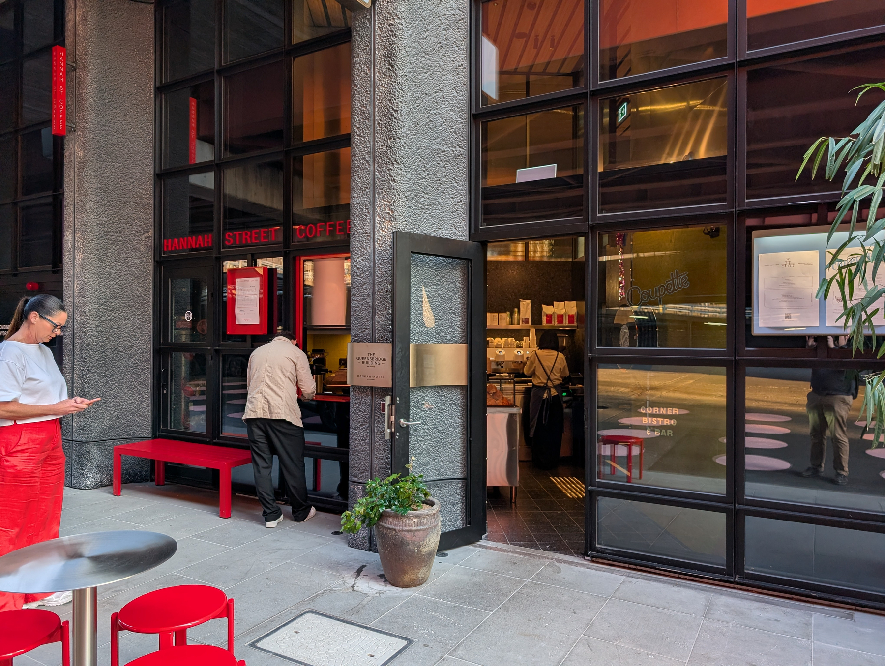 A coffee shop with a glass facade, with a man standing at the counter inside.