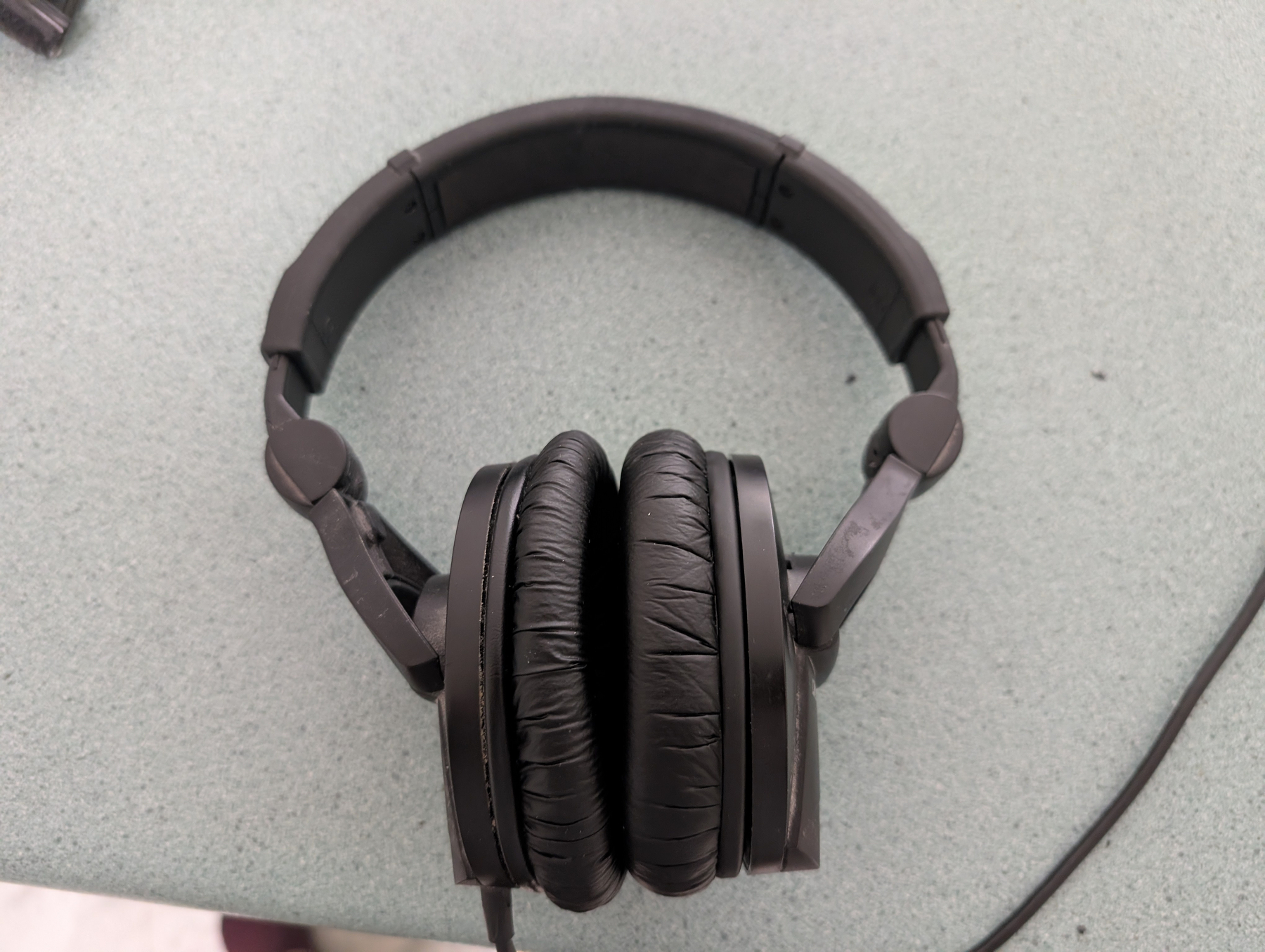 Auto-generated description: A pair of black over-ear headphones is resting on a light gray surface.