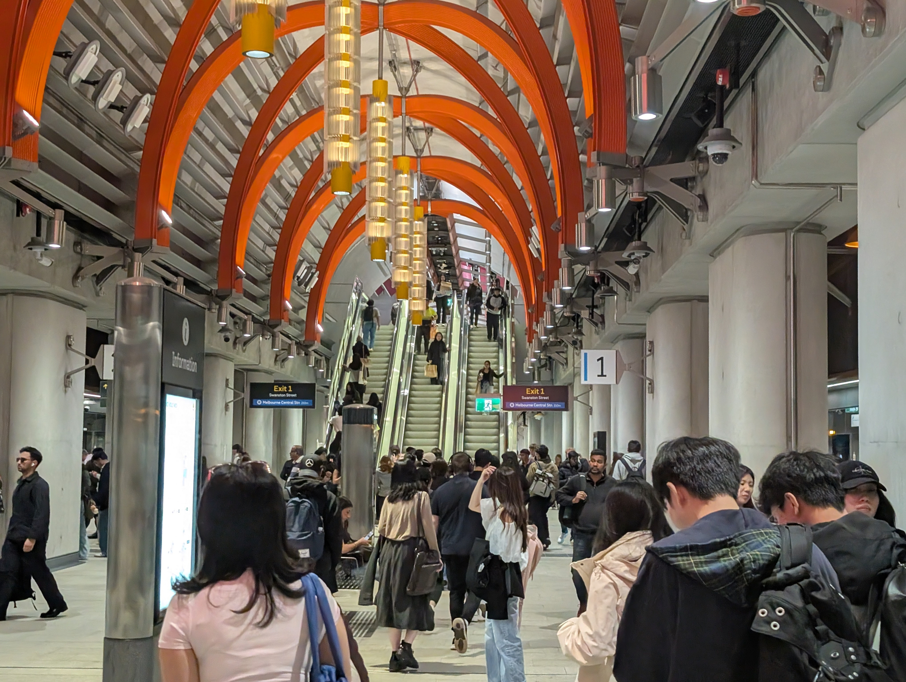 The platforms of State Library station with a crowd of people moving towards the escalators.