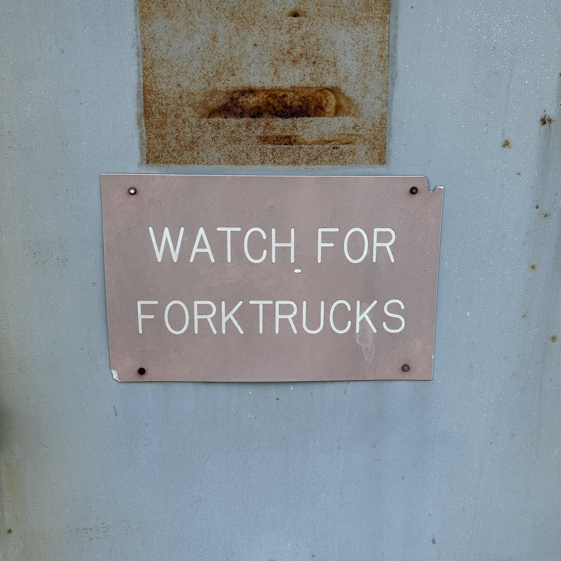 Watch for fork trucks sign on a door at a manufacturing building.