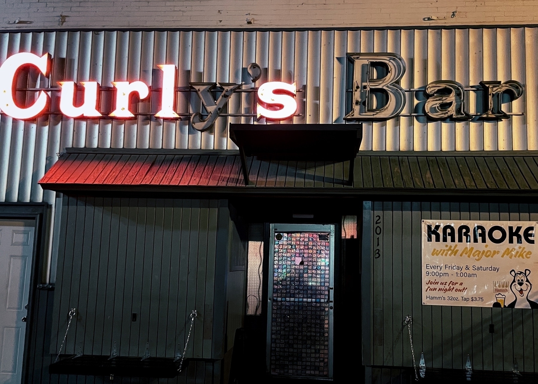 Outside building with neon lettering for ‘Curly’s Bar’