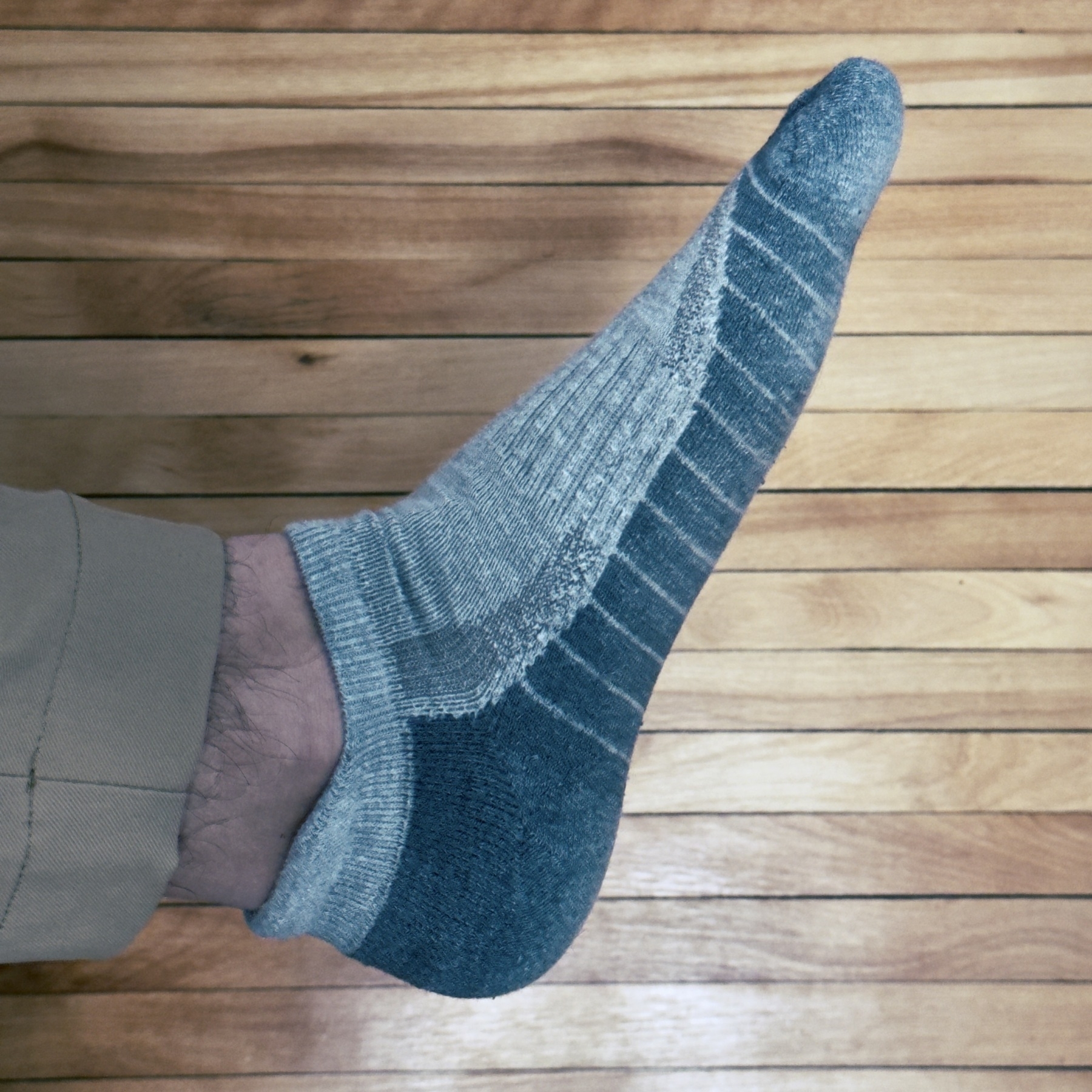 image of a socked foot raised over a natural wood floor
