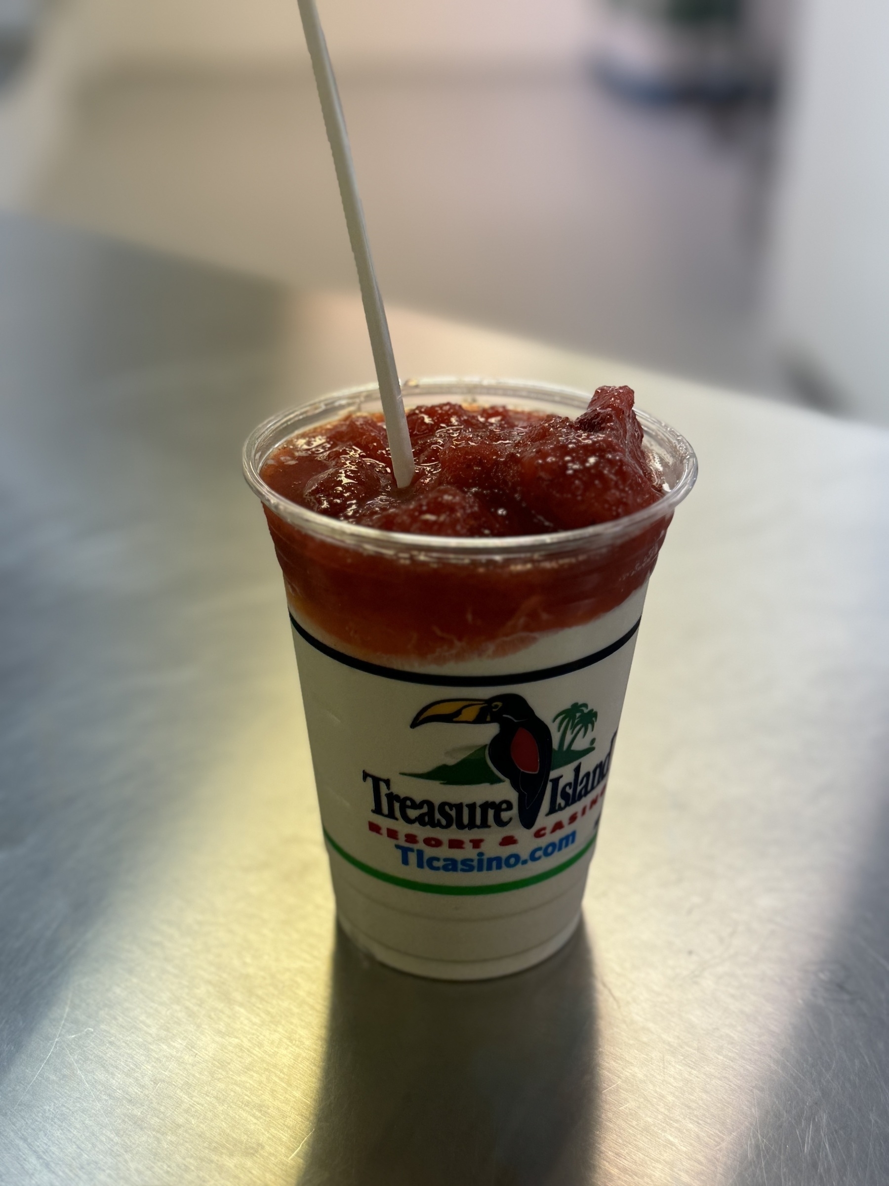 a strawberry layered malt in a plastic cup with Treasure Island casino advertising logo