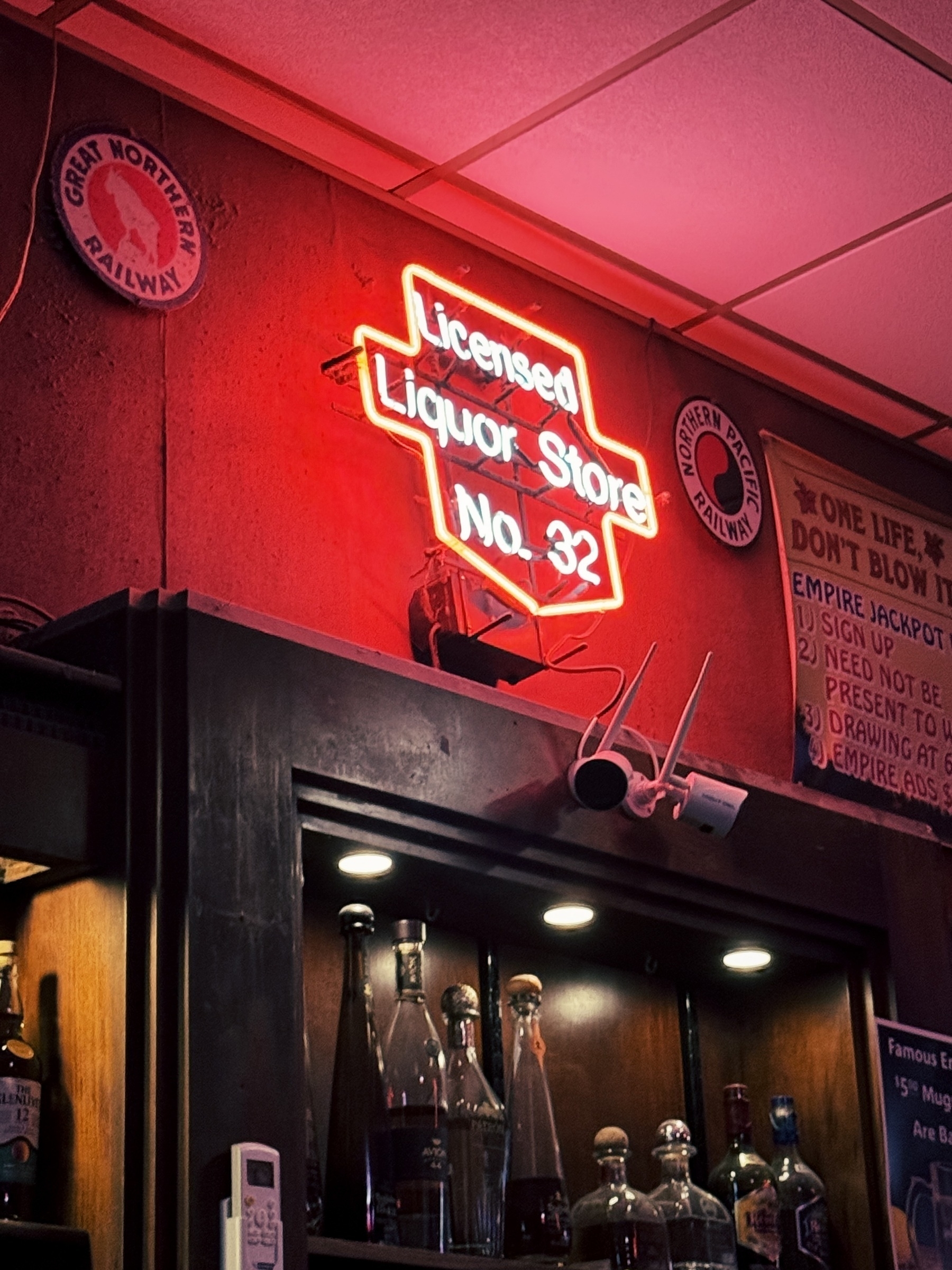 Glowing red neon light inside bar that reads Licensed Liquor Store No. 32
