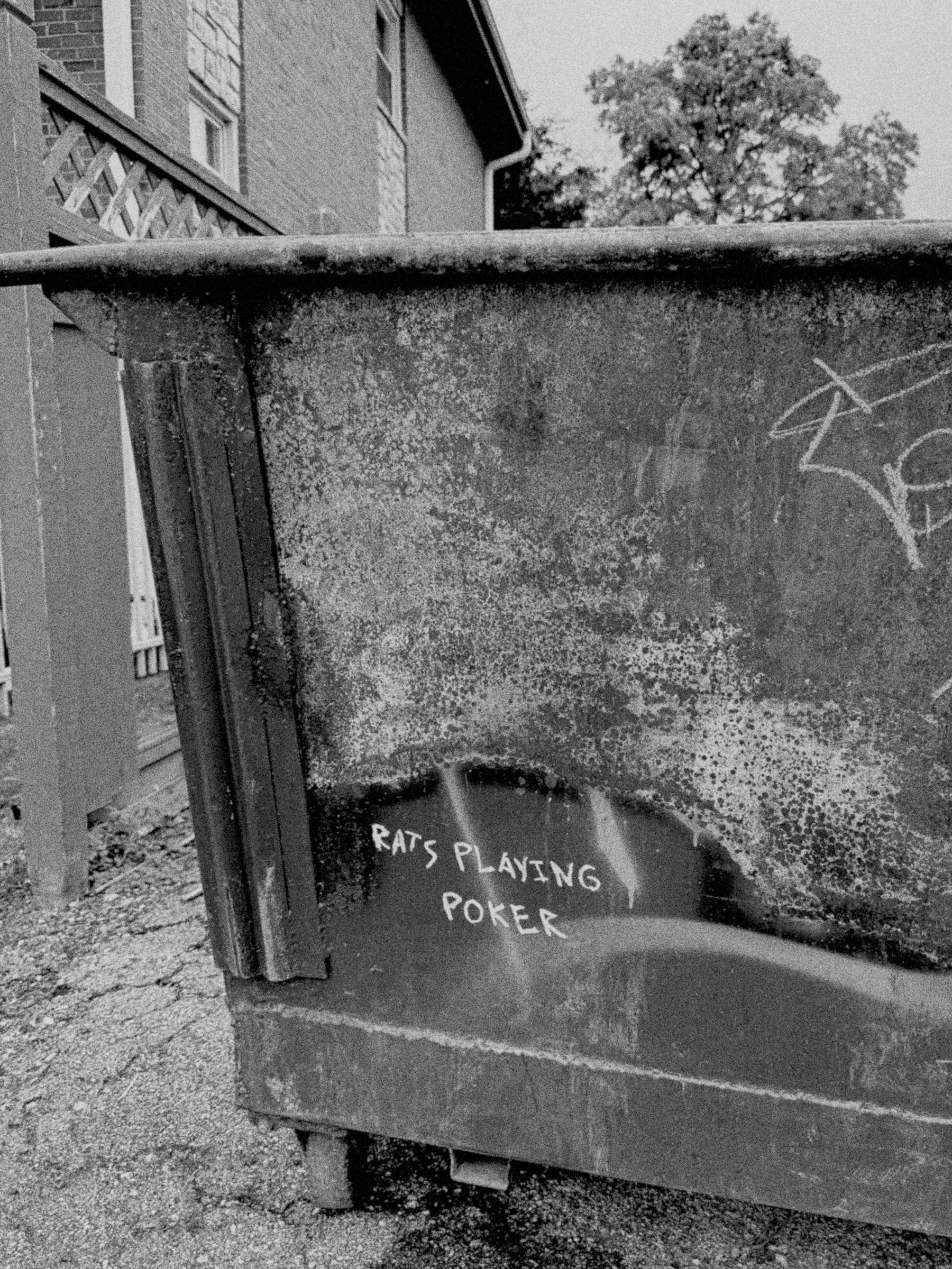 A rusty dumpster features graffiti with the text RATS PLAYING POKER on its side, location: Kansas City. (Filtered through AgBr app)