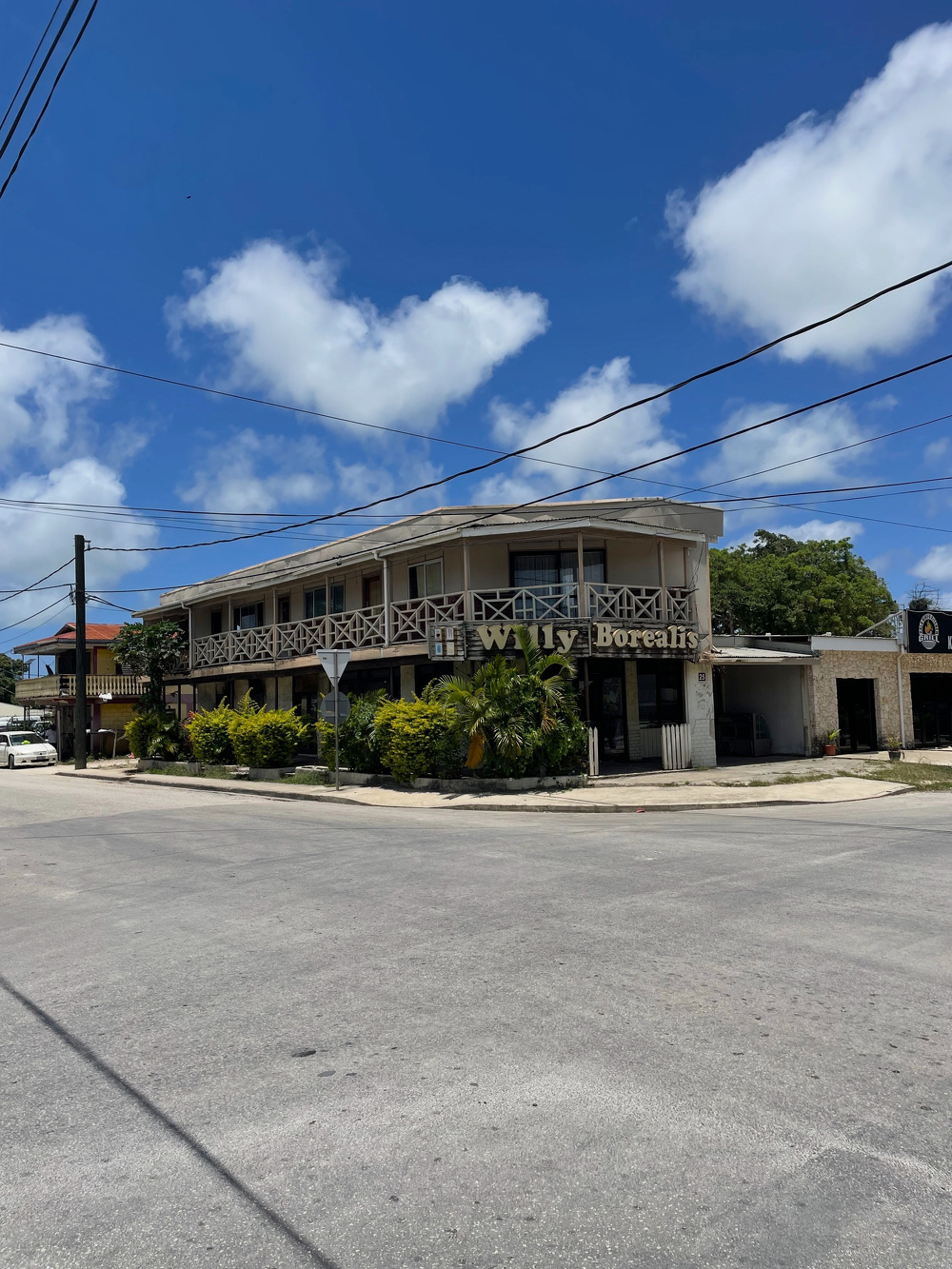 A two-story building labeled Wally's and Borealis is situated on a sunny street corner with a blue sky and scattered clouds above.