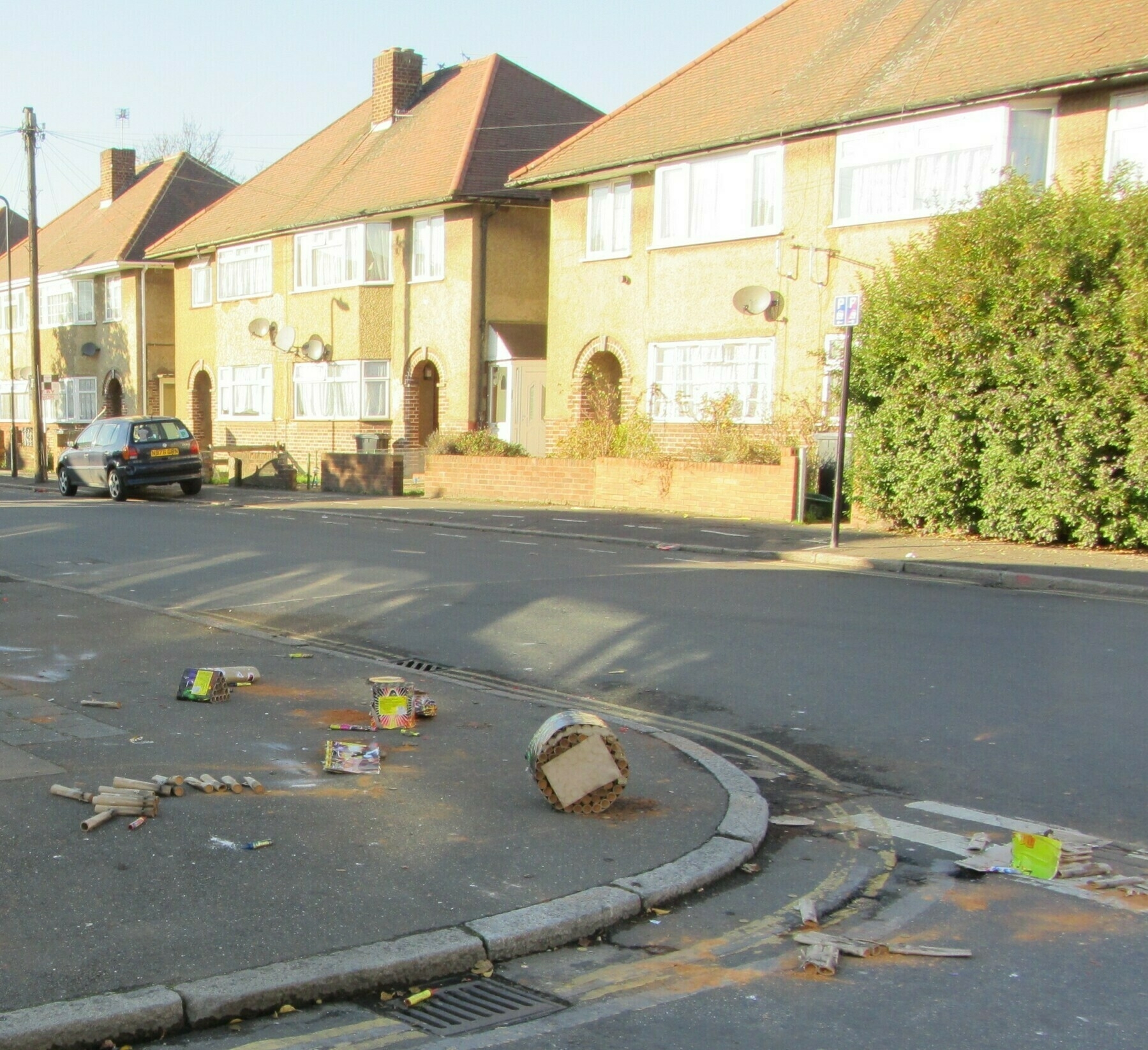 Street corner littered with fireworks detritus, opposite terraced houses.