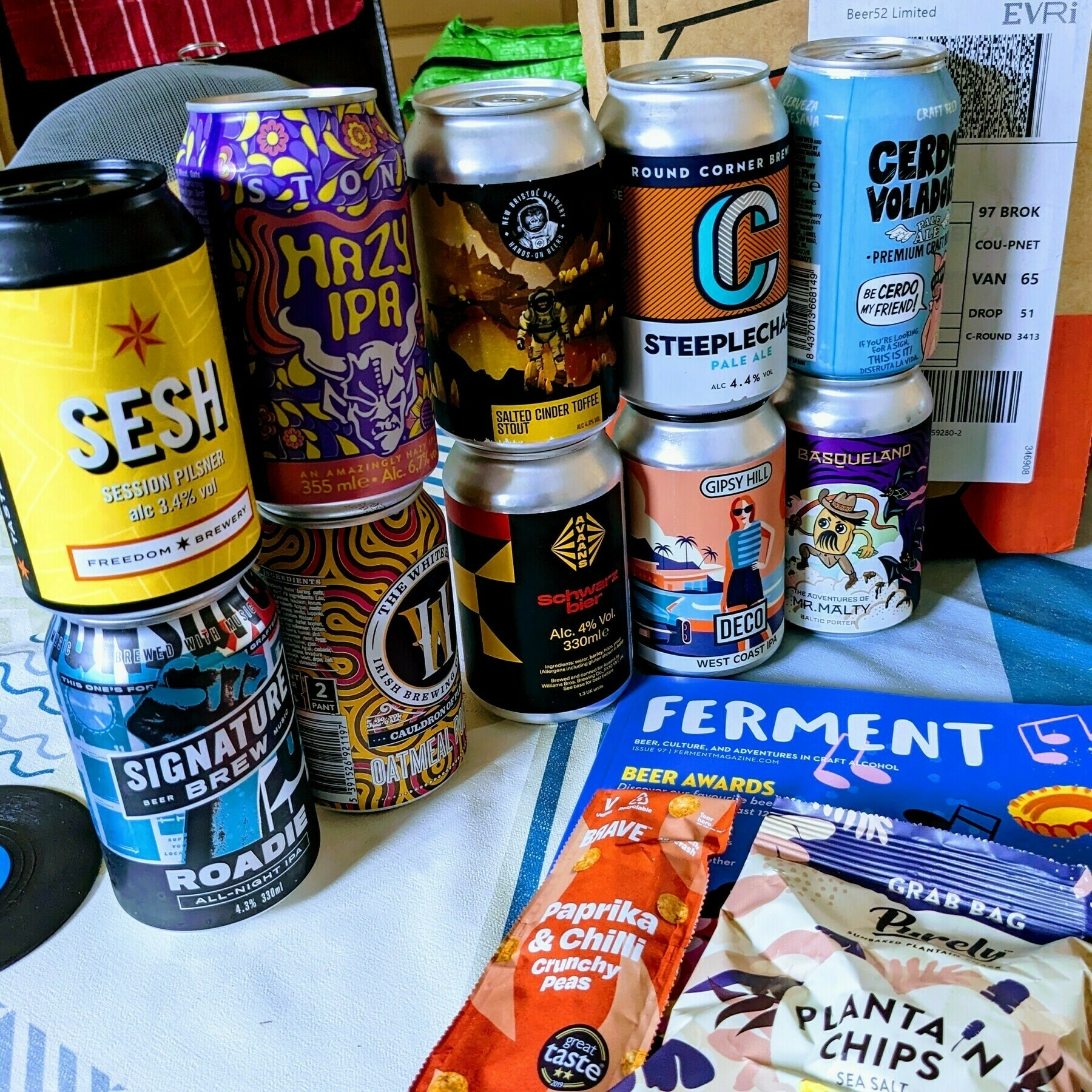 Ten colourful cans of light and dark craft beers stacked in twos alongside the Evri delivery box they arrived in, a copy of 'Ferment' magazine and a couple of 'free' snacks thrown in.