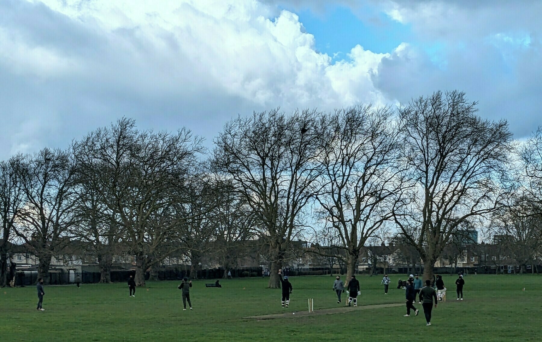 Men playing cricket in the park on a cold, wet and blustery Sunday afternoon in early February 