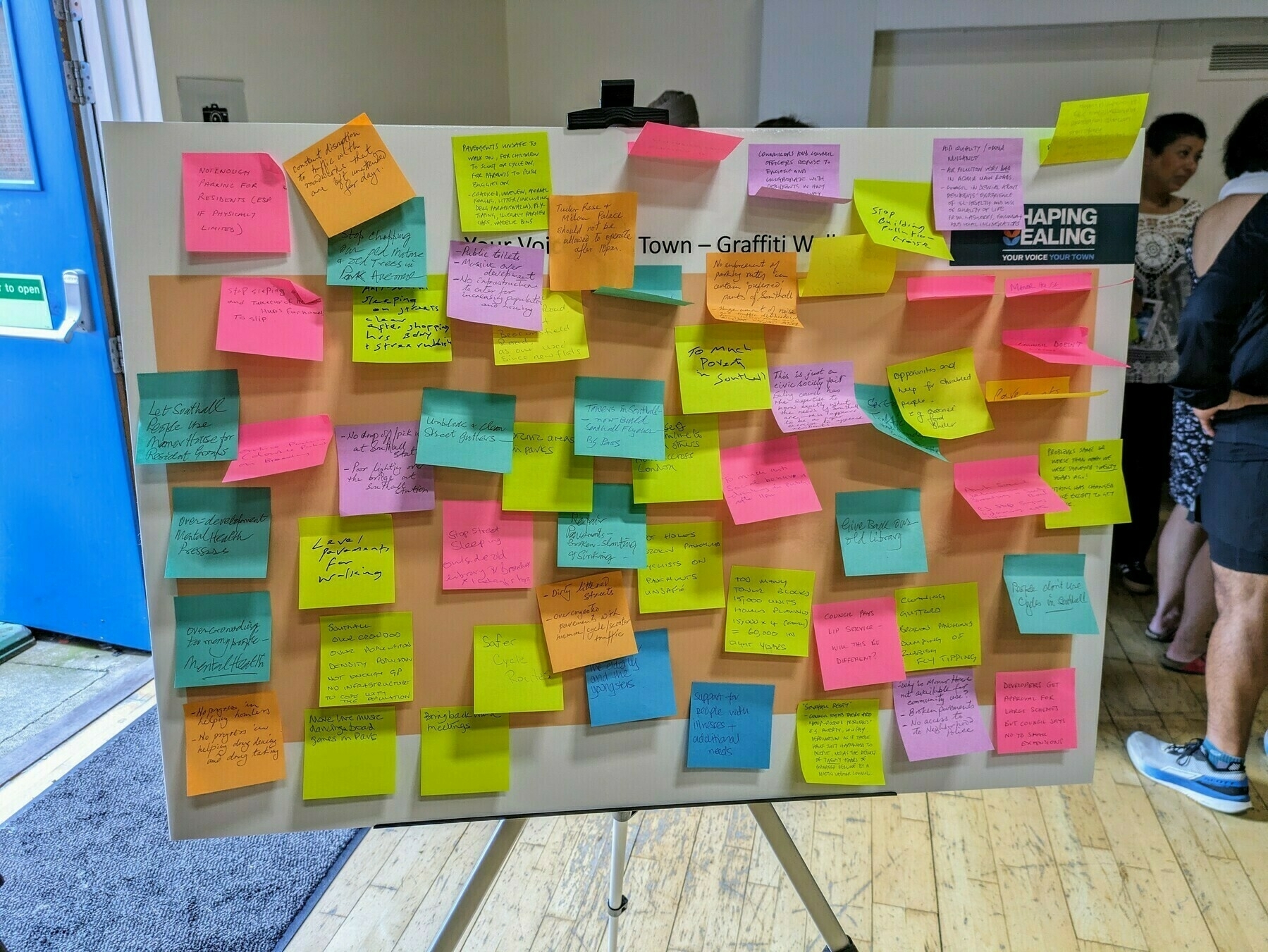 Photo of 'graffiti board' covered in multi-coloured post-it notes with comments from residents