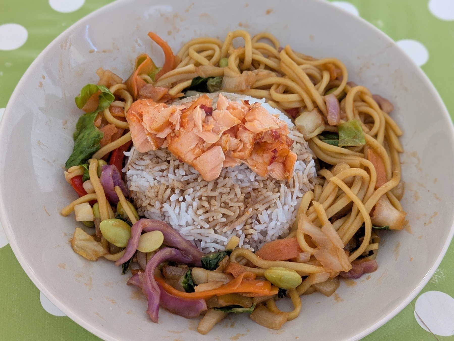 Chilli salmon on a mound of boiled rice surrounded by egg noodles and stir fried vegetables in a soy and ginger sauce