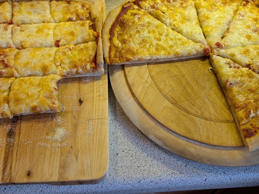 Two types of pizza, one cut into rectangular slices and the other into triangular slices, are placed on separate wooden boards.