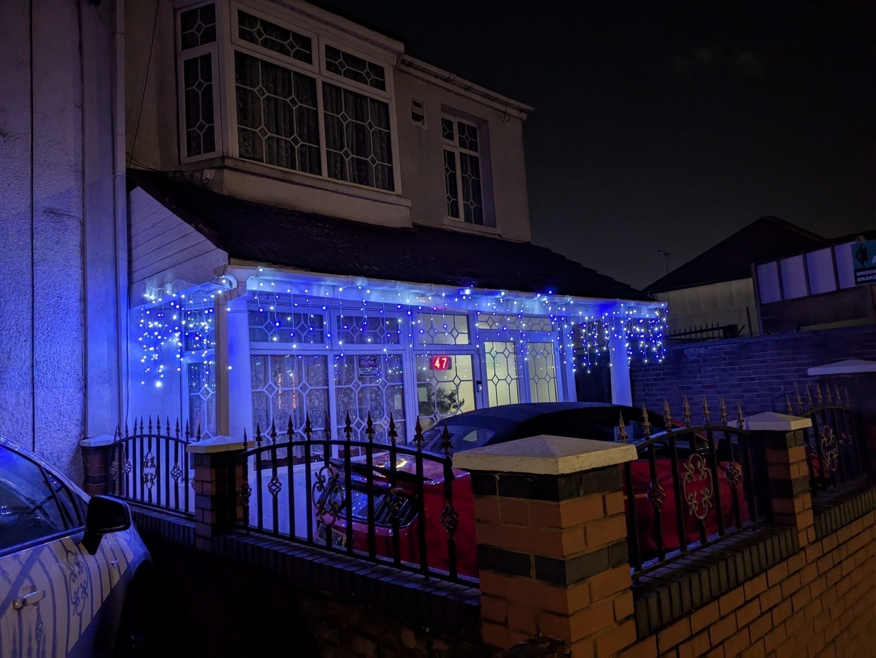 A house is decorated with blue string lights hanging from the porch at night.