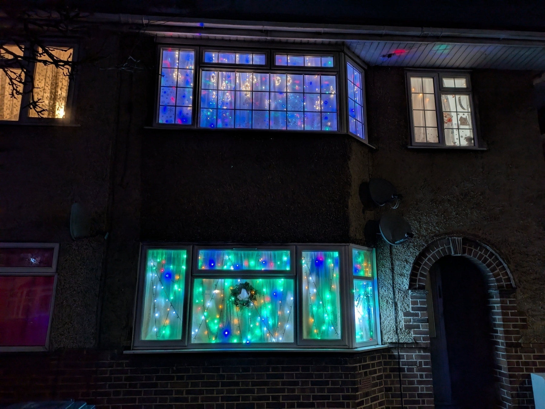 A house is decorated with colorful LED lights illuminating the windows at night.