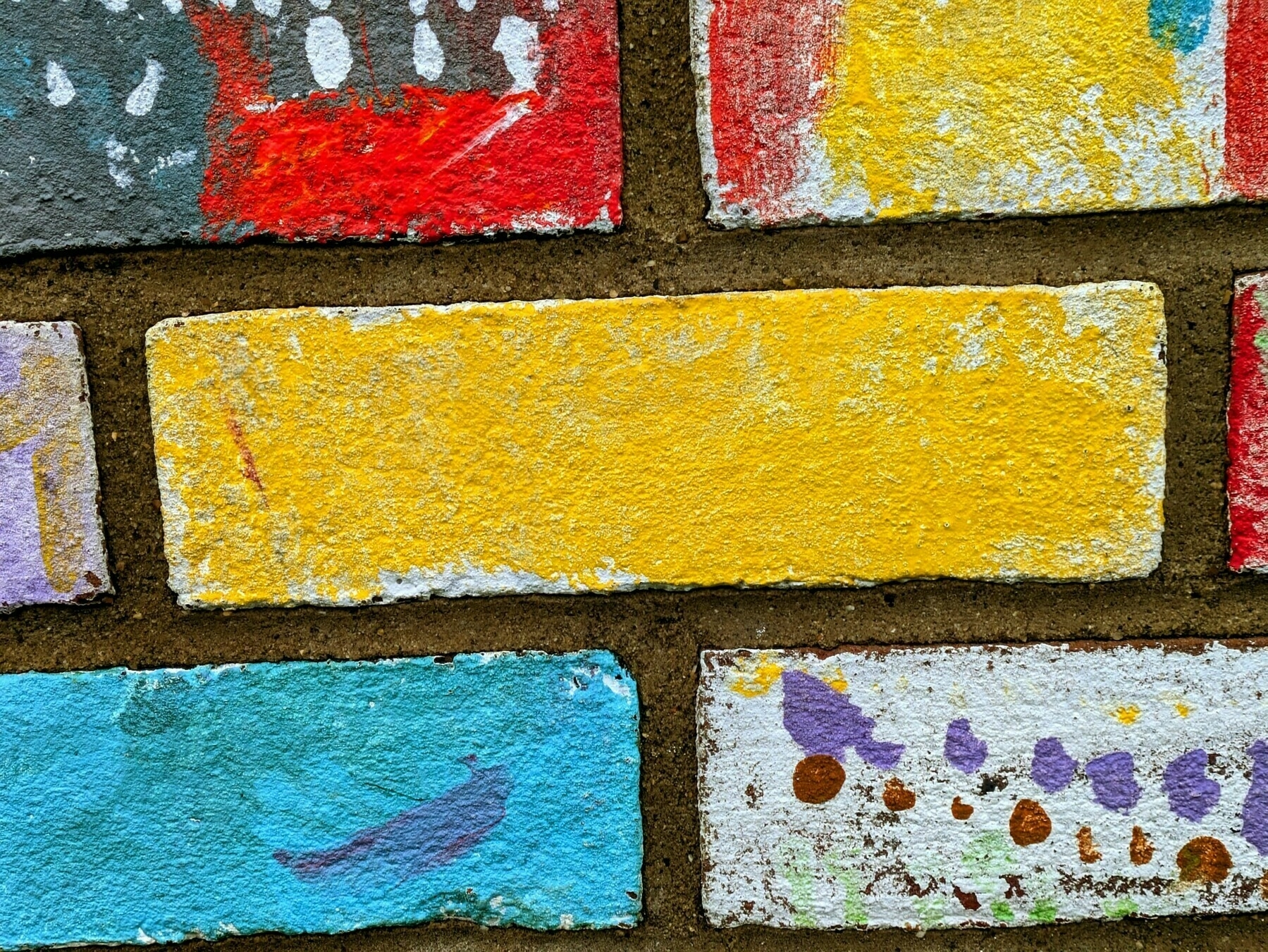 Auto-generated description: Colorfully painted bricks feature designs in red, yellow, blue, and other hues.