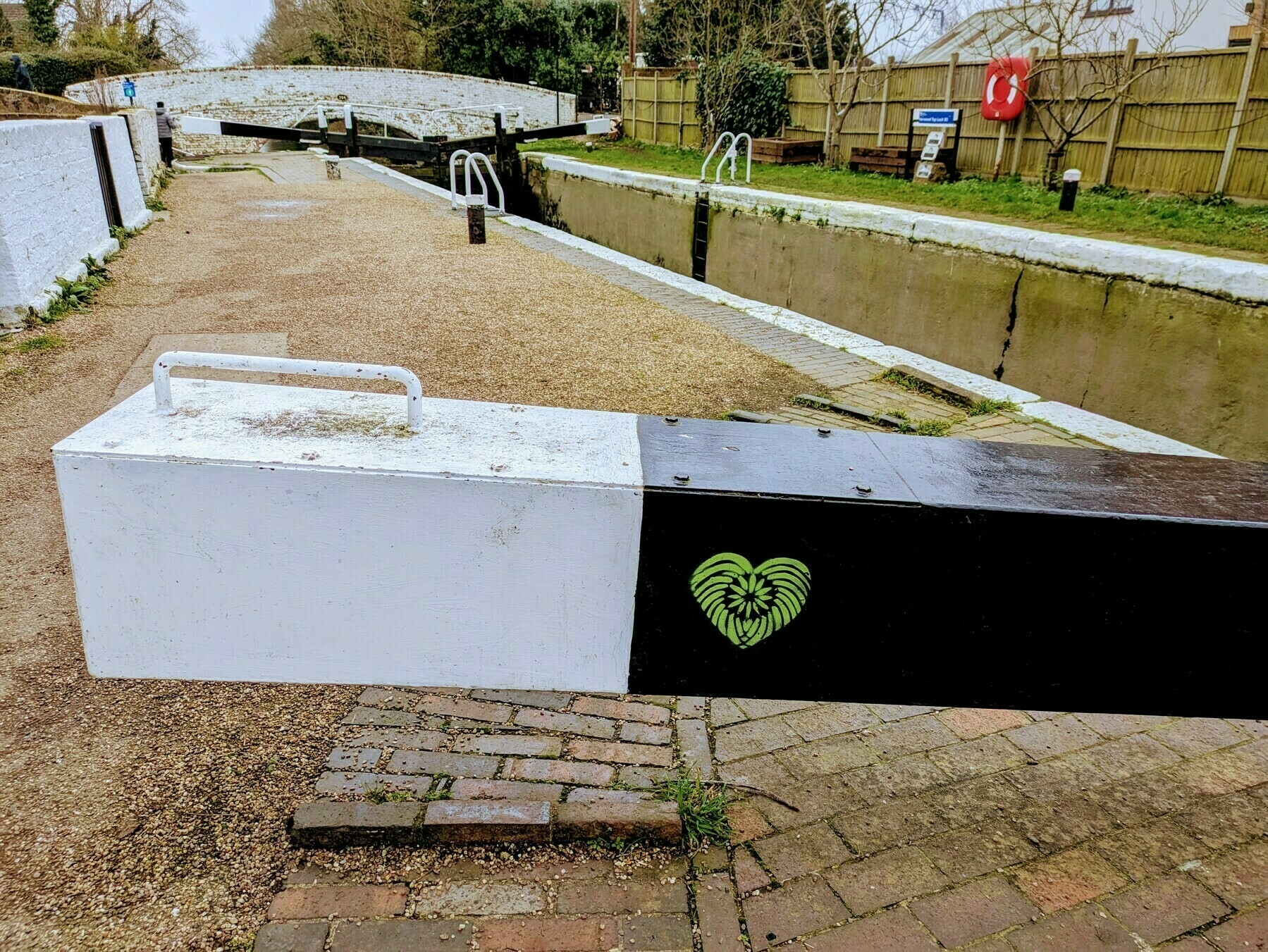 A canal lock with a walkway and a heart-shaped design painted on a barrier is shown.