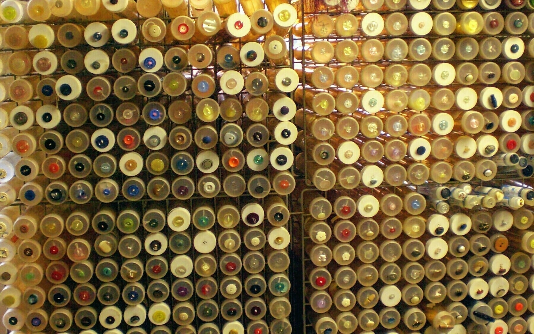 Auto-generated description: A collection of multicolored spools of thread arranged on a storage rack.