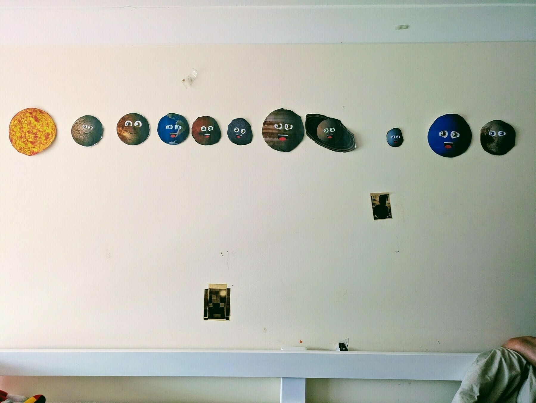 A series of circular cutouts depicting planets with googly eyes are arranged on a wall, representing the solar system.