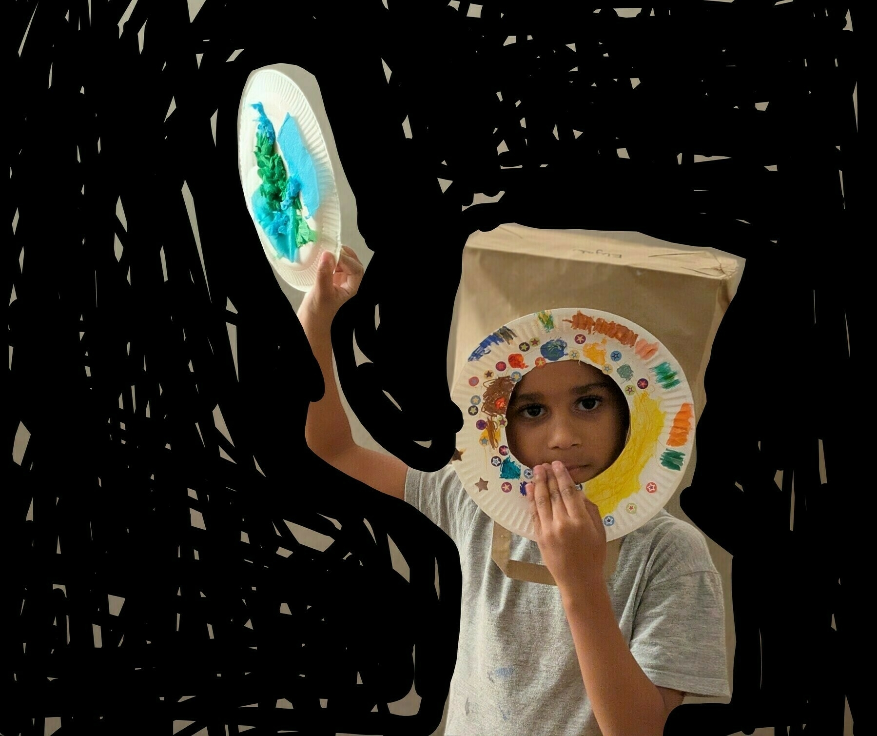 Auto-generated description: A child is dressed as an astronaut with a homemade space helmet and is holding a paper plate designed like a planet.