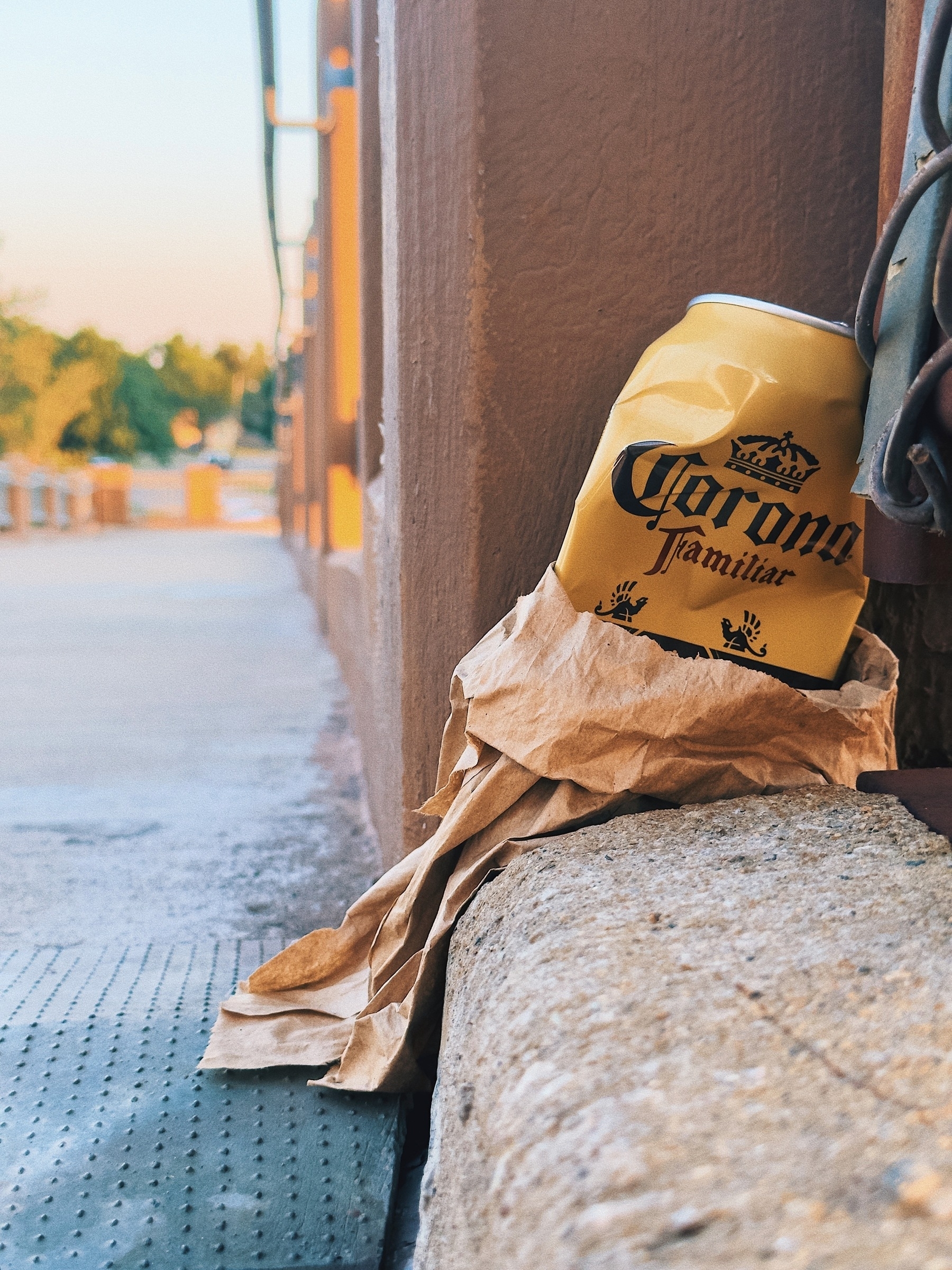 A closeup of a crumpled can of Corona Familiar in a paper bag