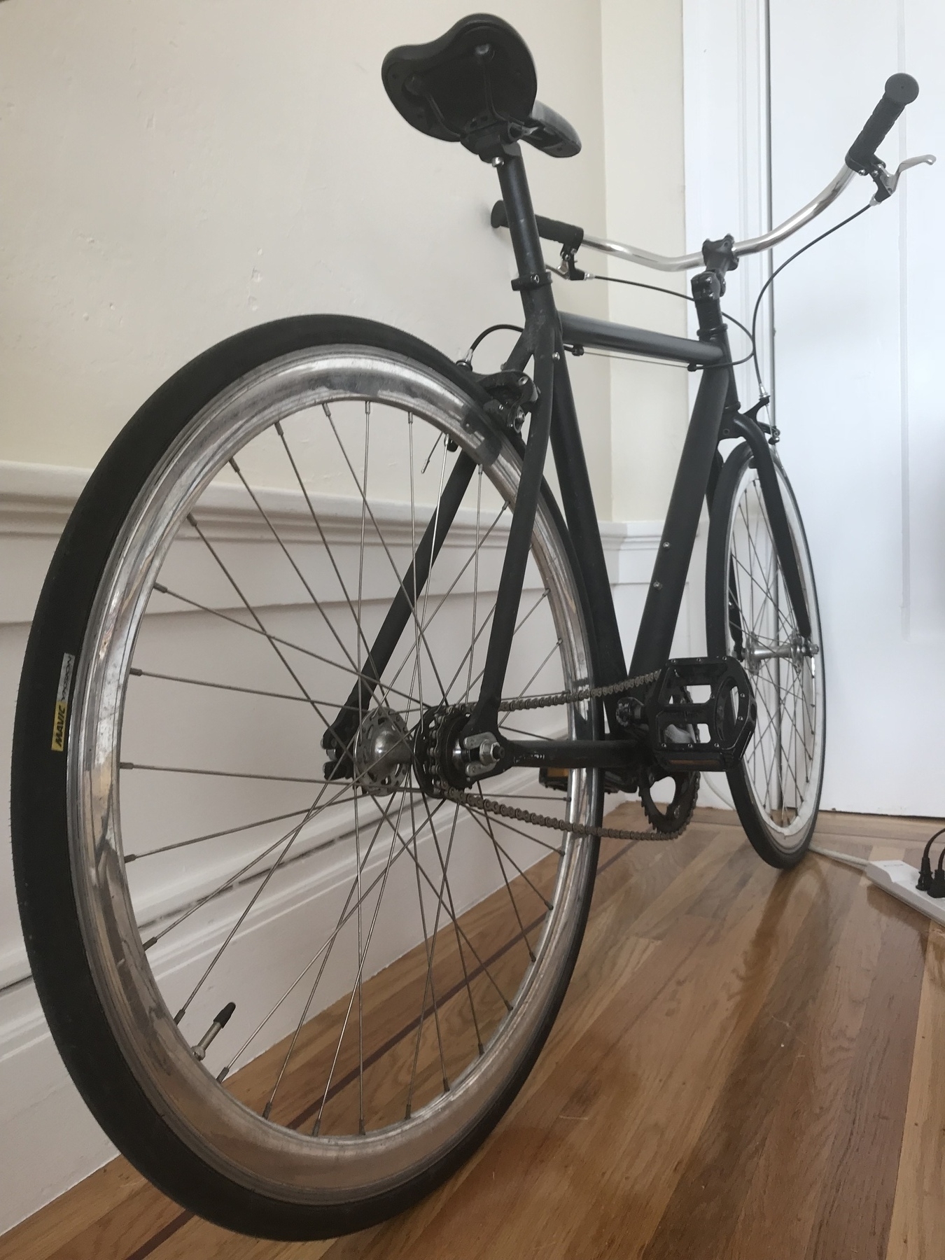 A single speed bike lining against the wall 