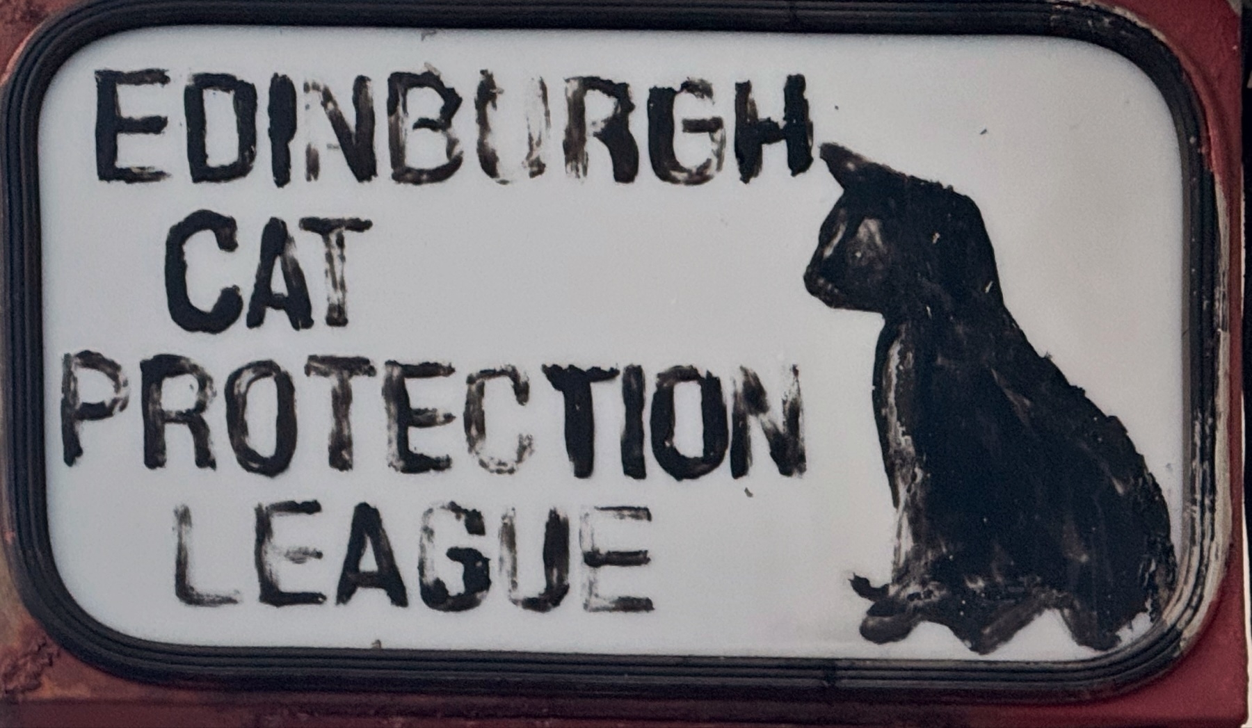 A sign with the text "EDINBURGH CAT PROTECTION LEAGUE" and a silhouette of a sitting cat on the right.