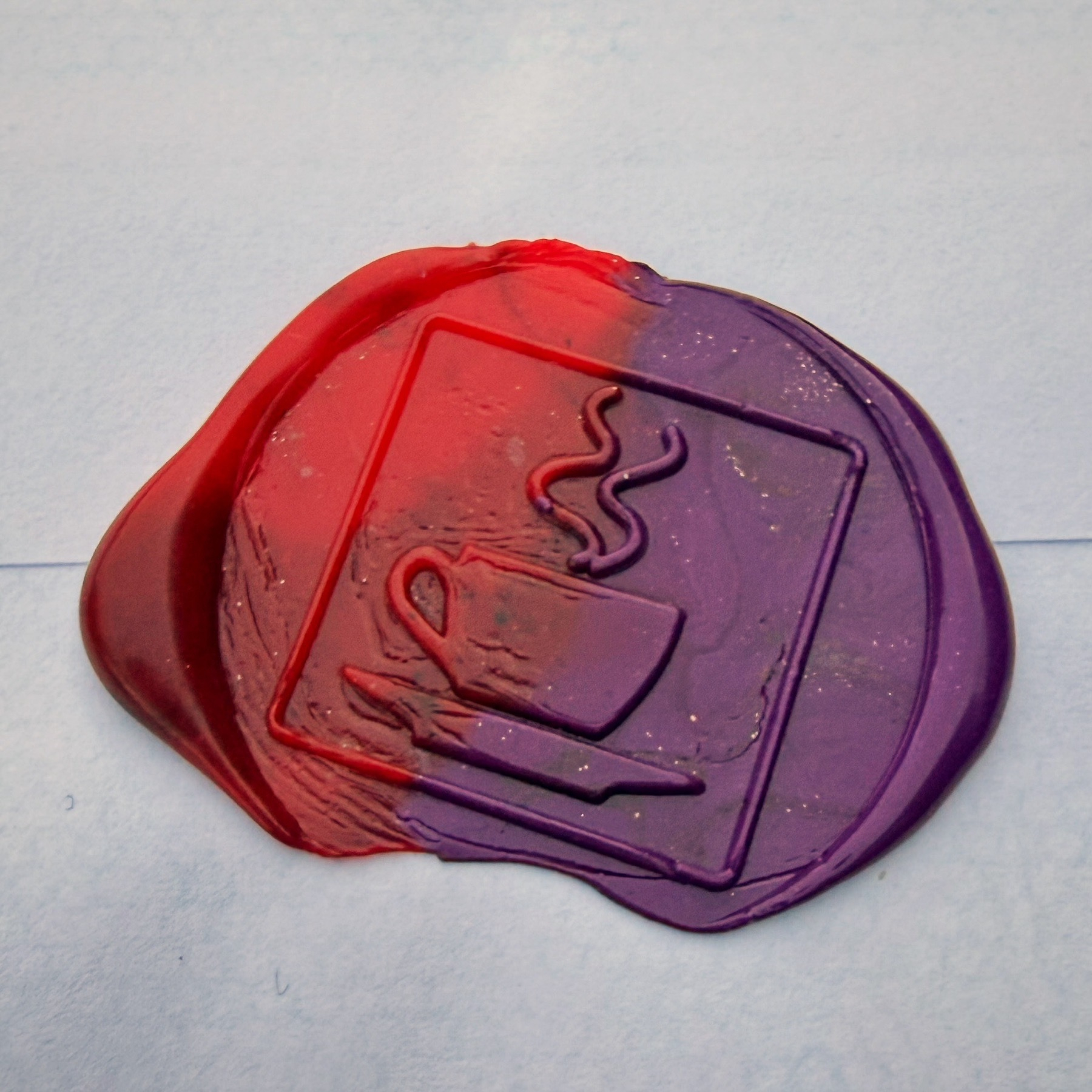 Wax seal of a steaming coffee cup in red and purple.