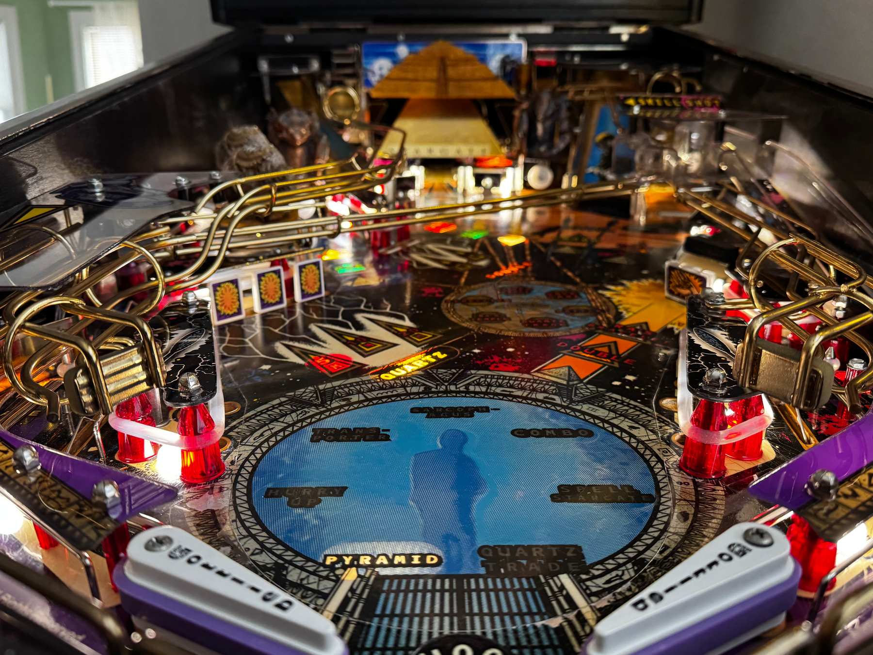 A colorful pinball machine playfield featuring intricate details and ramps, with an Egyptian pyramid theme.