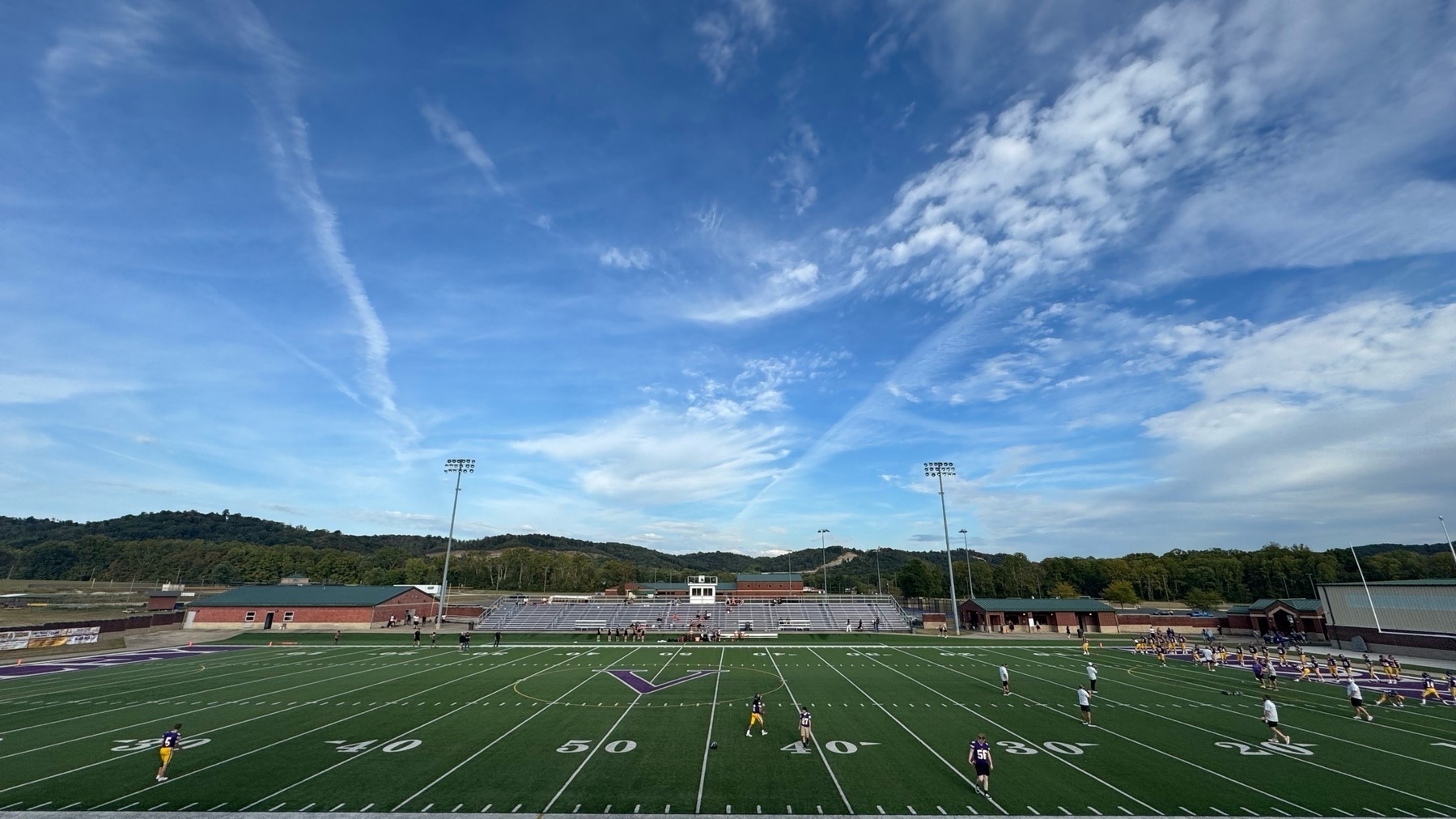 A high school football field. Clouds in a blue sky. 