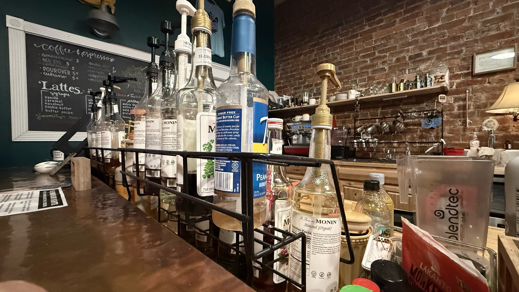 A coffee bar with flavor syrups, signs and such in the background. 