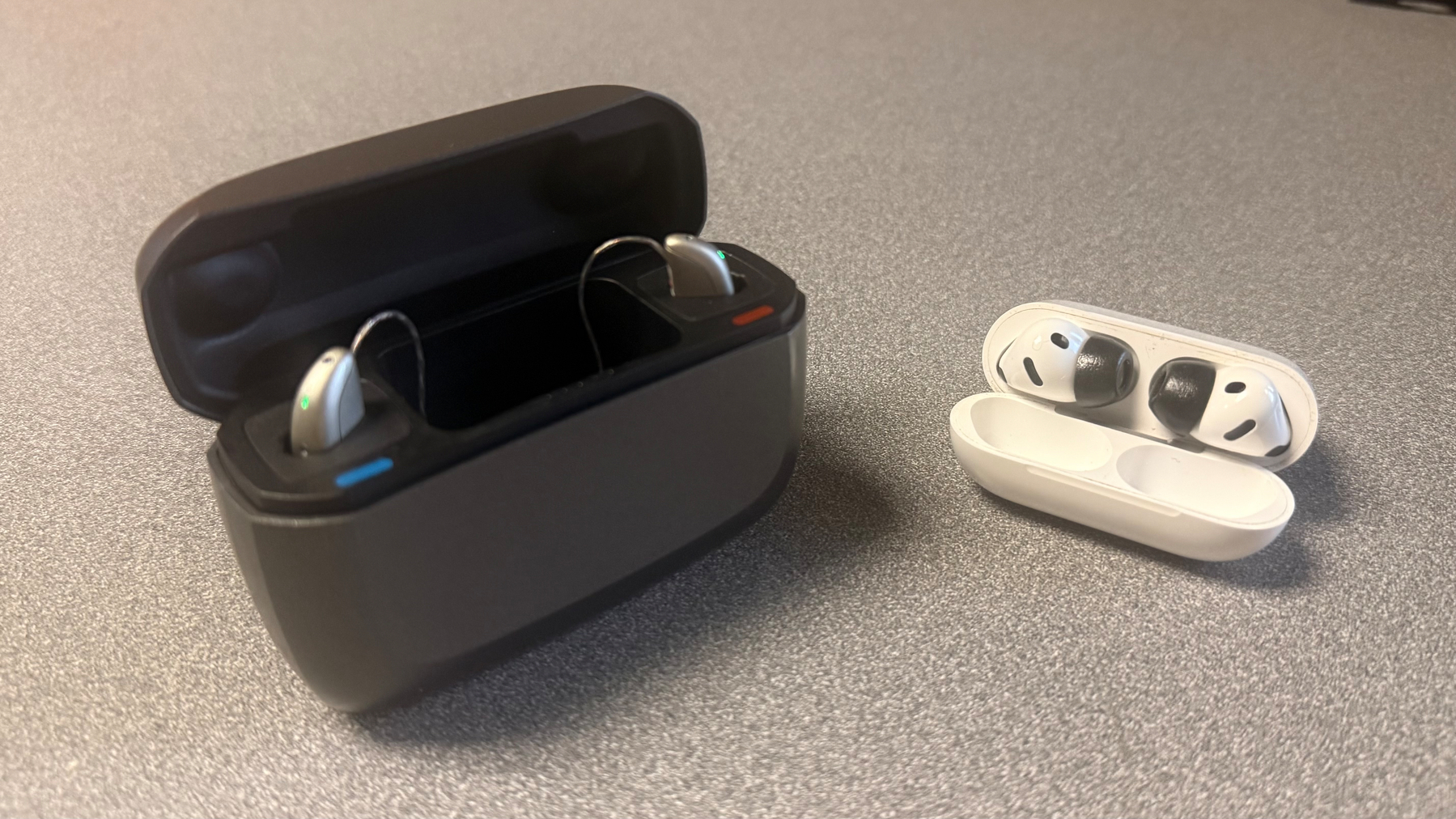 The Jabra enhance 700 hearing aids versus AirPods Pro 3 on a table. 