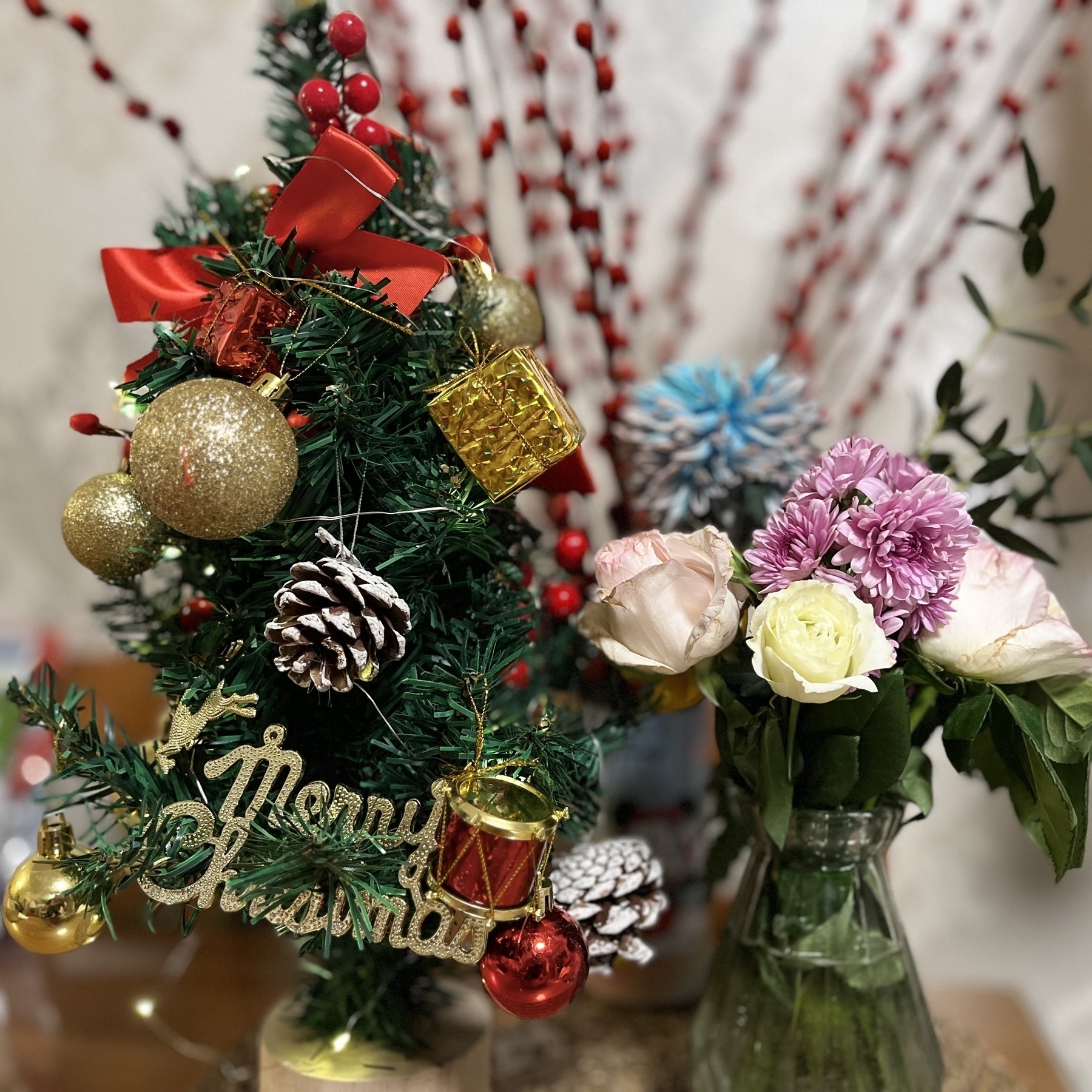 Hamer and I decorated a small Christmas tree. (A small Christmas tree decorated with ornaments is next to a vase of colorful flowers.)