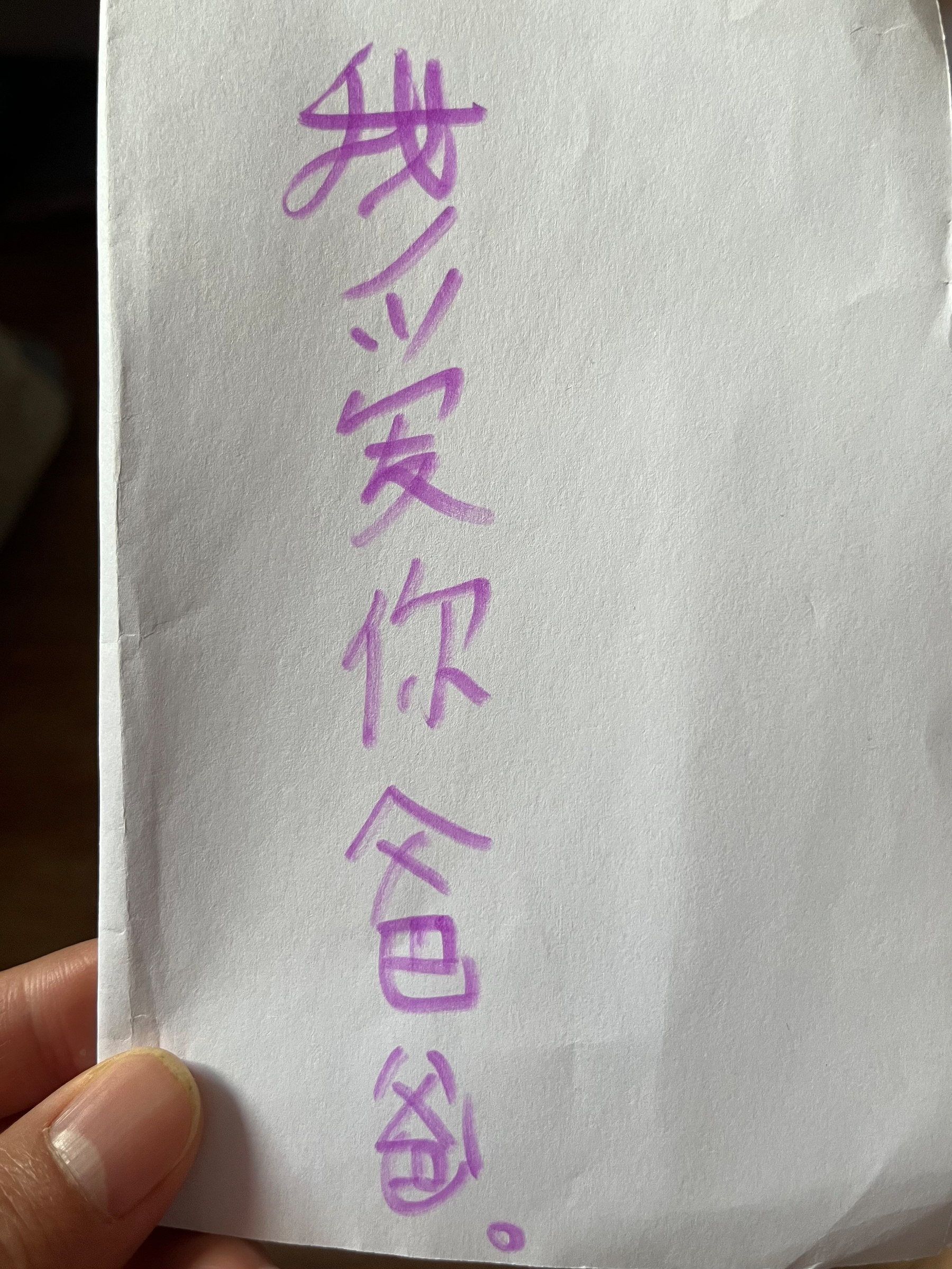A hand is holding a piece of paper with handwritten Chinese text (I love you, Dad) in purple ink.