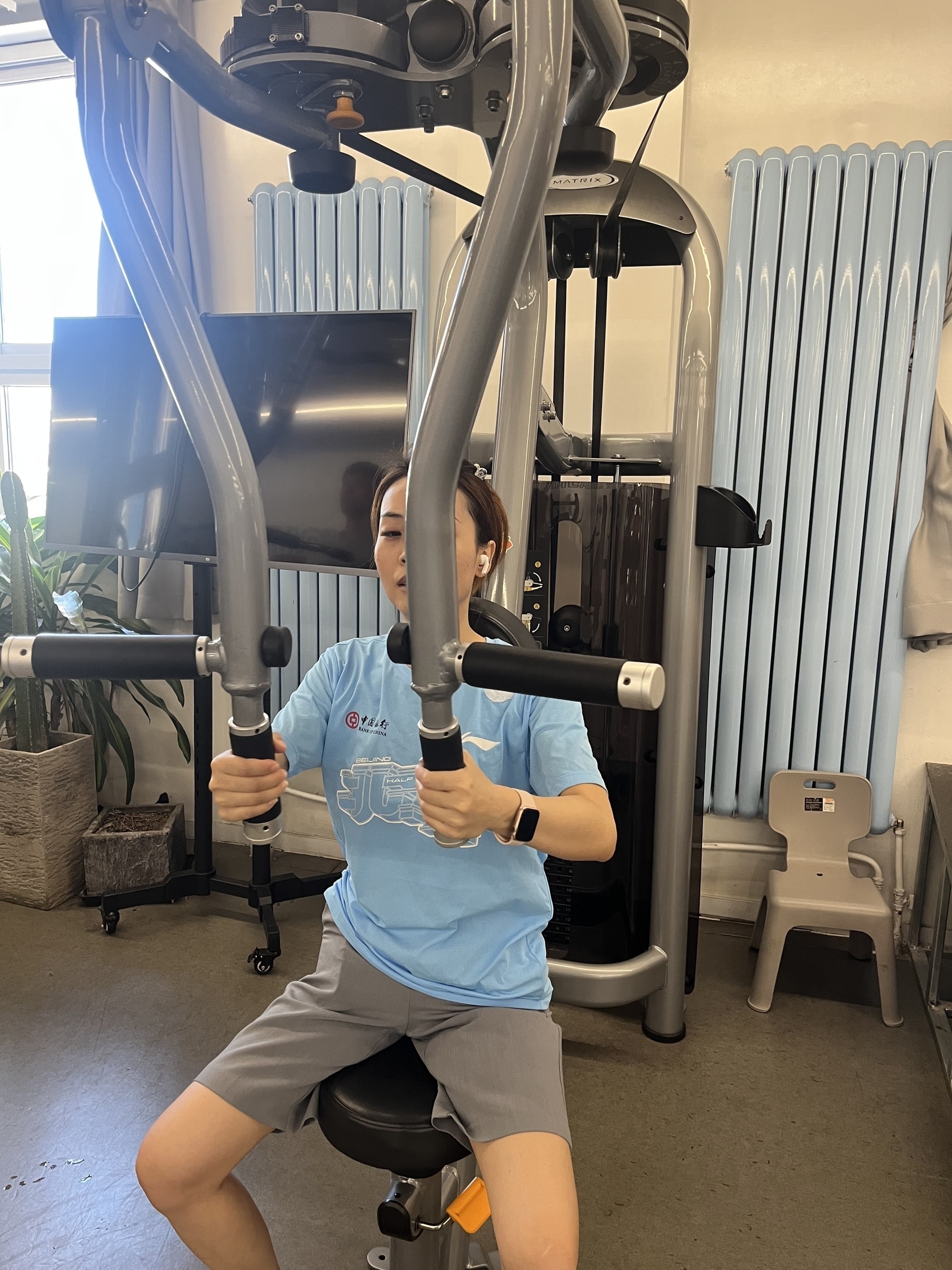 A person is using a chest press machine at the gym.