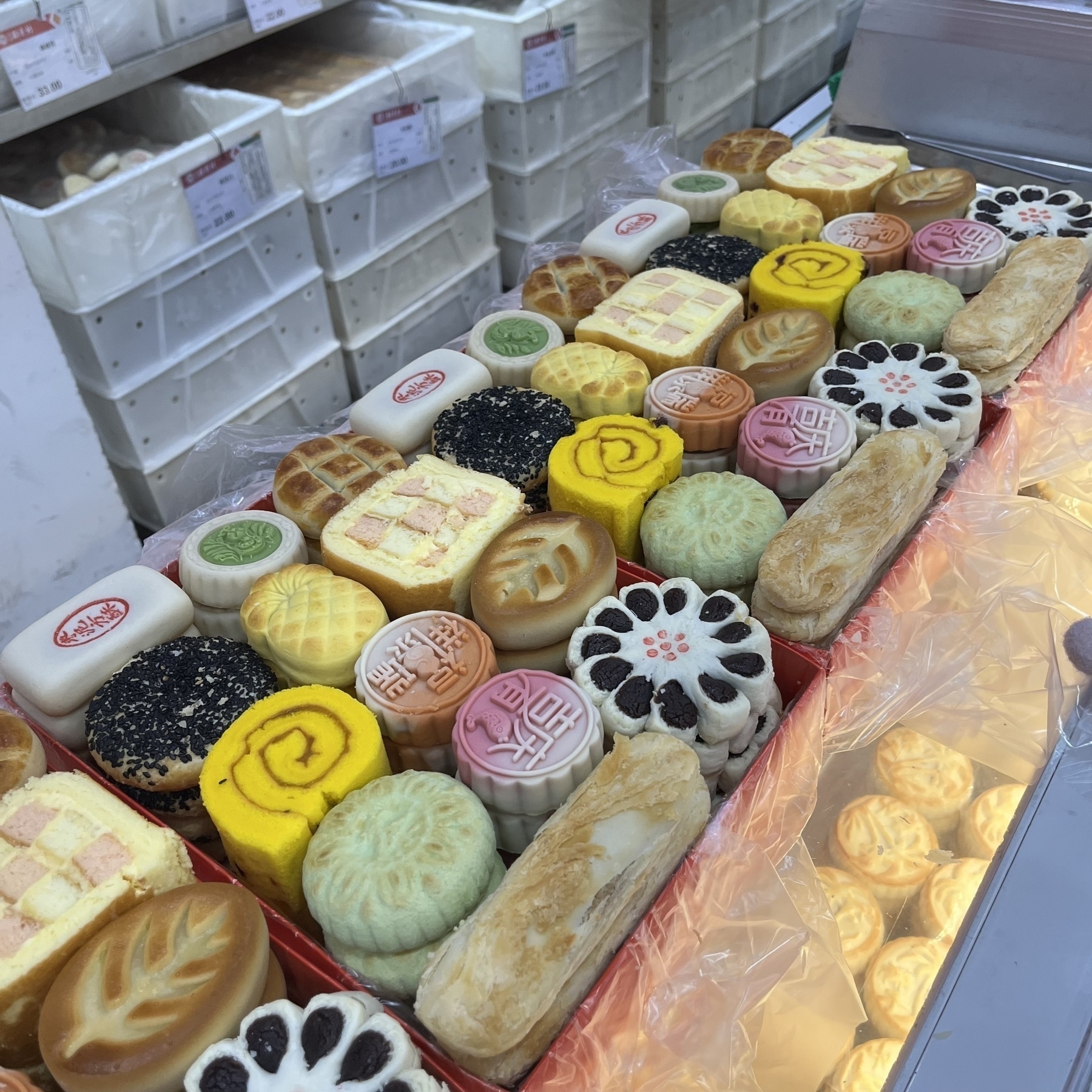 The pastries from Daoxiangcun are arranged neatly and orderly.(A variety of colorful and intricately designed pastries are displayed in a bakery.)