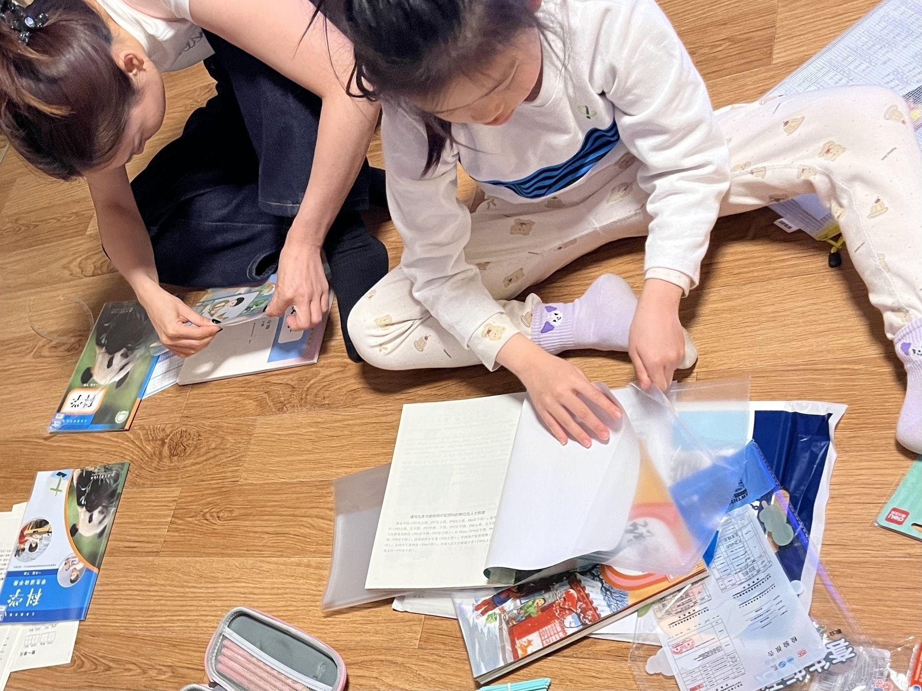 Hamer spent the evening organizing her supplies until 9:30 PM. (Two children are sitting on the floor organizing papers and school supplies.)