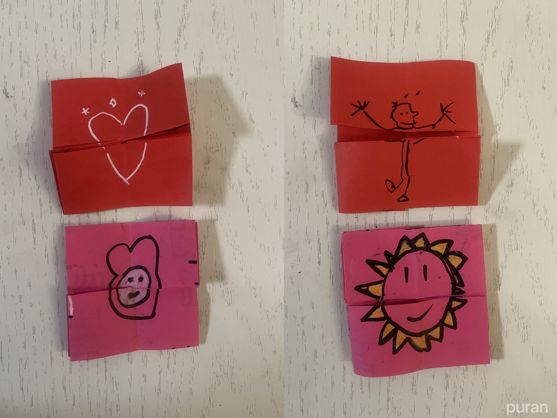 Four small origami fortune teller games feature simple doodles, including hearts and smiley faces, in red and pink paper.
