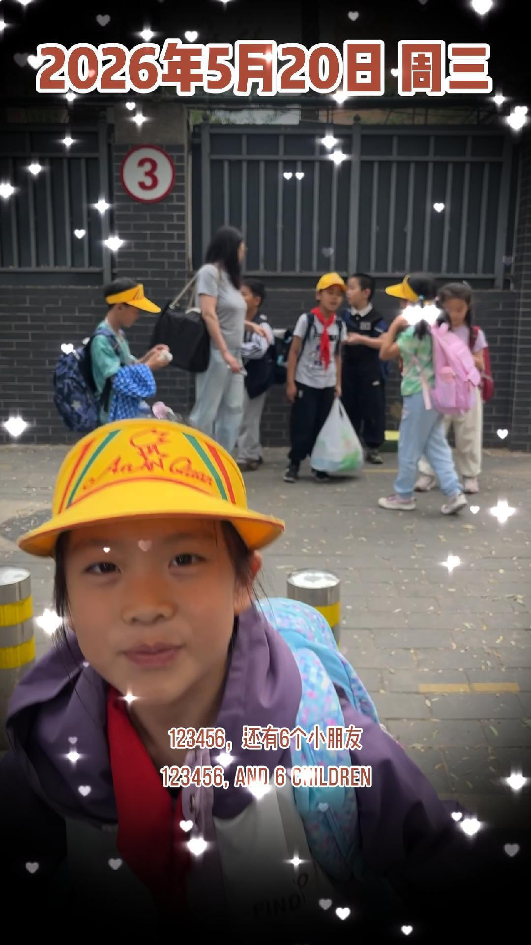 Children in yellow caps stand and walk near a building, with one child in the foreground smiling at the camera.