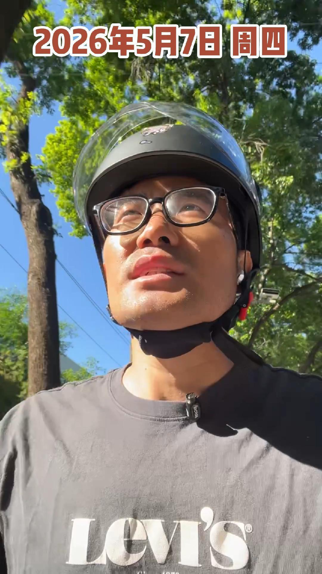 A person wearing a helmet and glasses is outdoors under a clear sky with green trees in the background, and there is text at the top of the image.