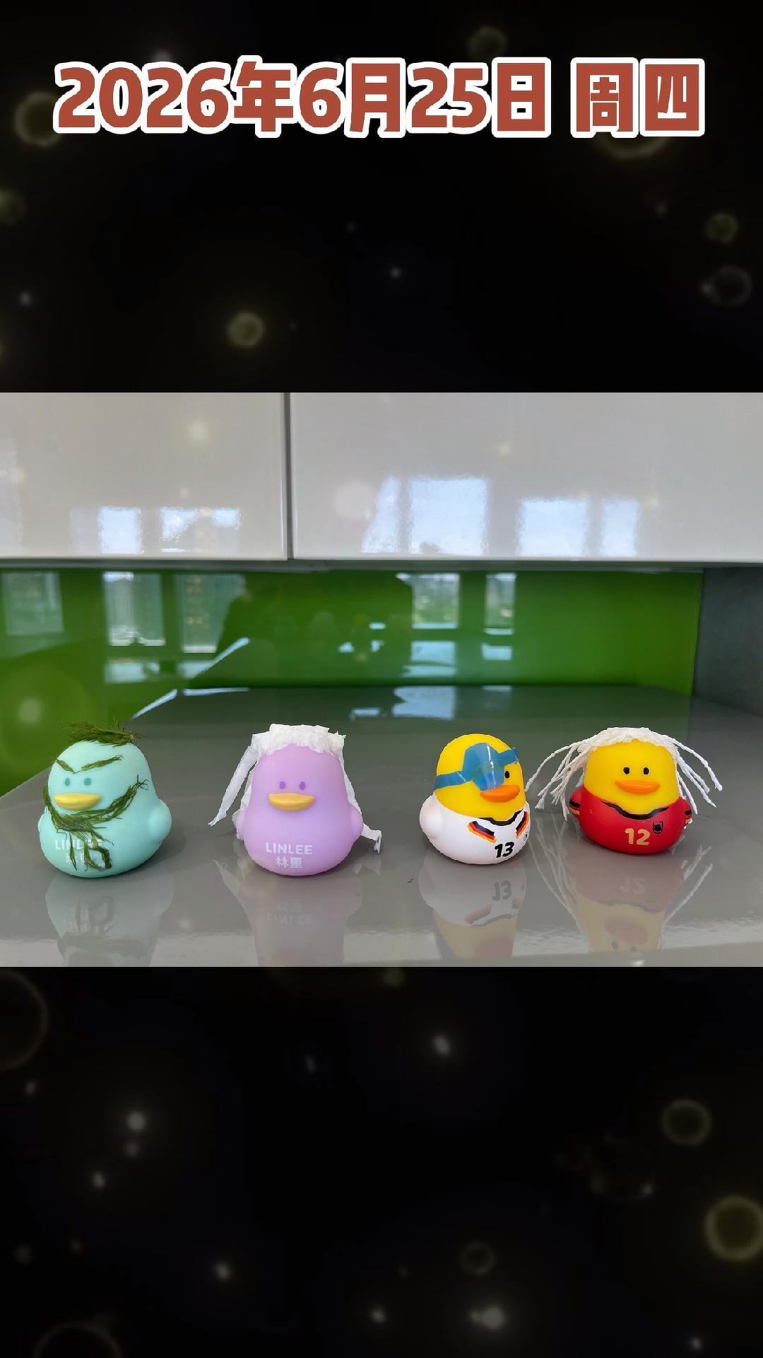 Four colorful rubber ducks, each with unique decorations such as painted faces and attached hair pieces, are lined up on a reflective surface in front of a green backsplash and white cabinets.