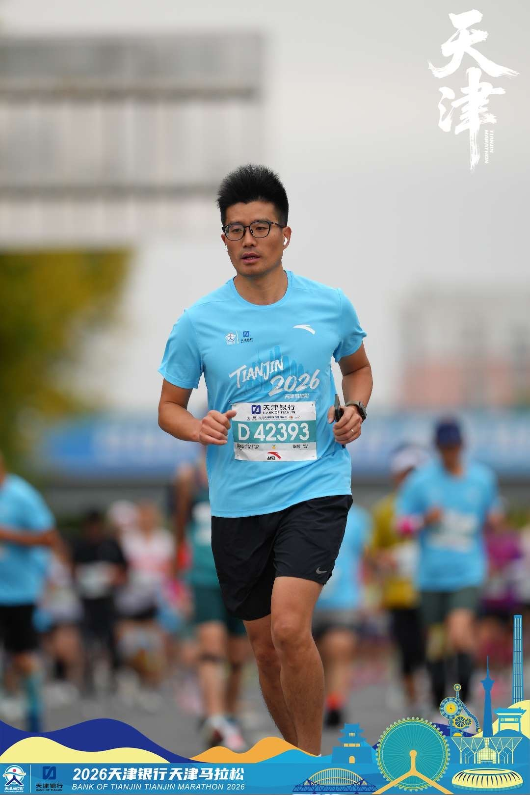 A male runner wearing a blue Tianjin 2026 shirt and black shorts is participating in a marathon race.