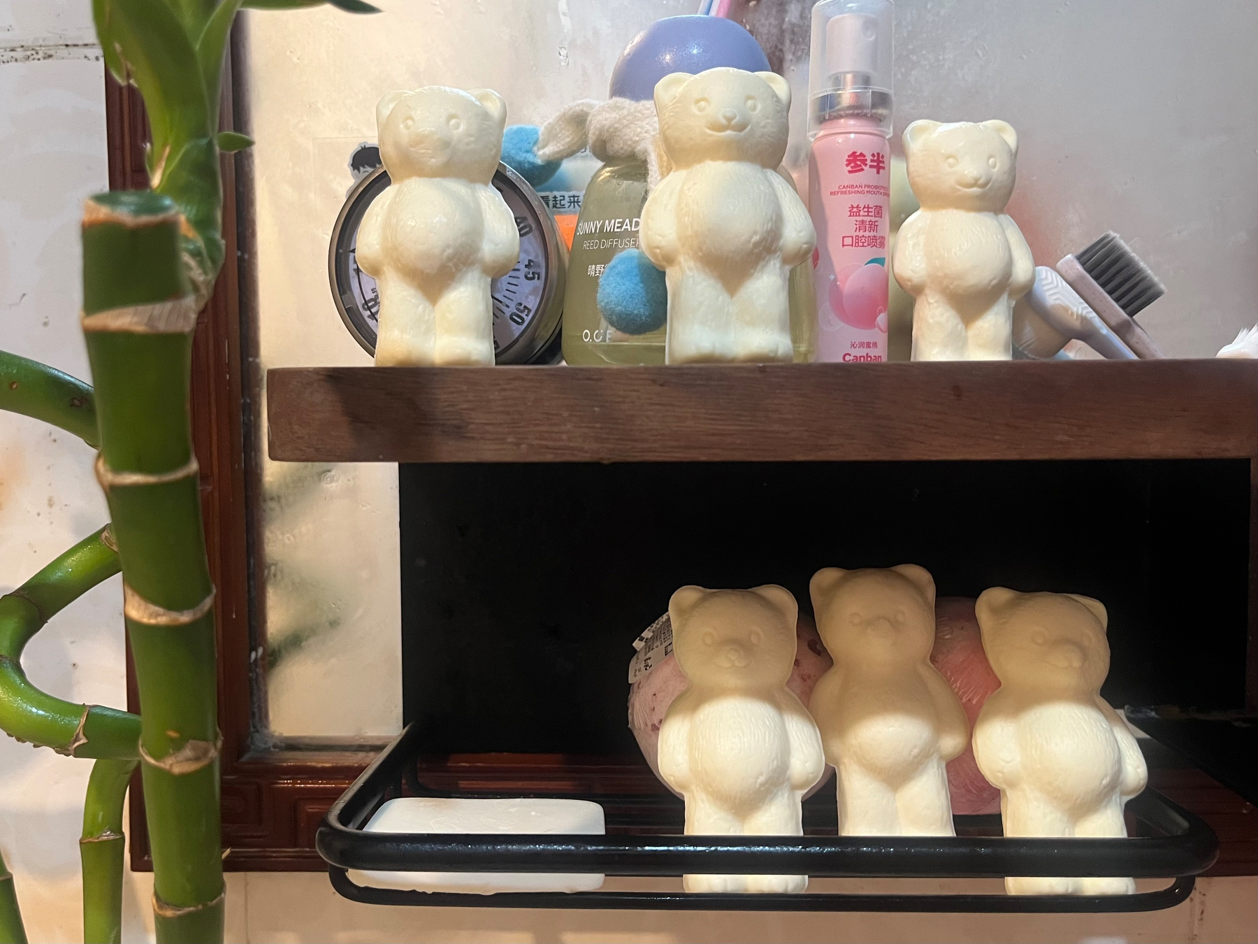 Several white bear-shaped objects are arranged on a bathroom shelf alongside toiletries and a toothbrush.