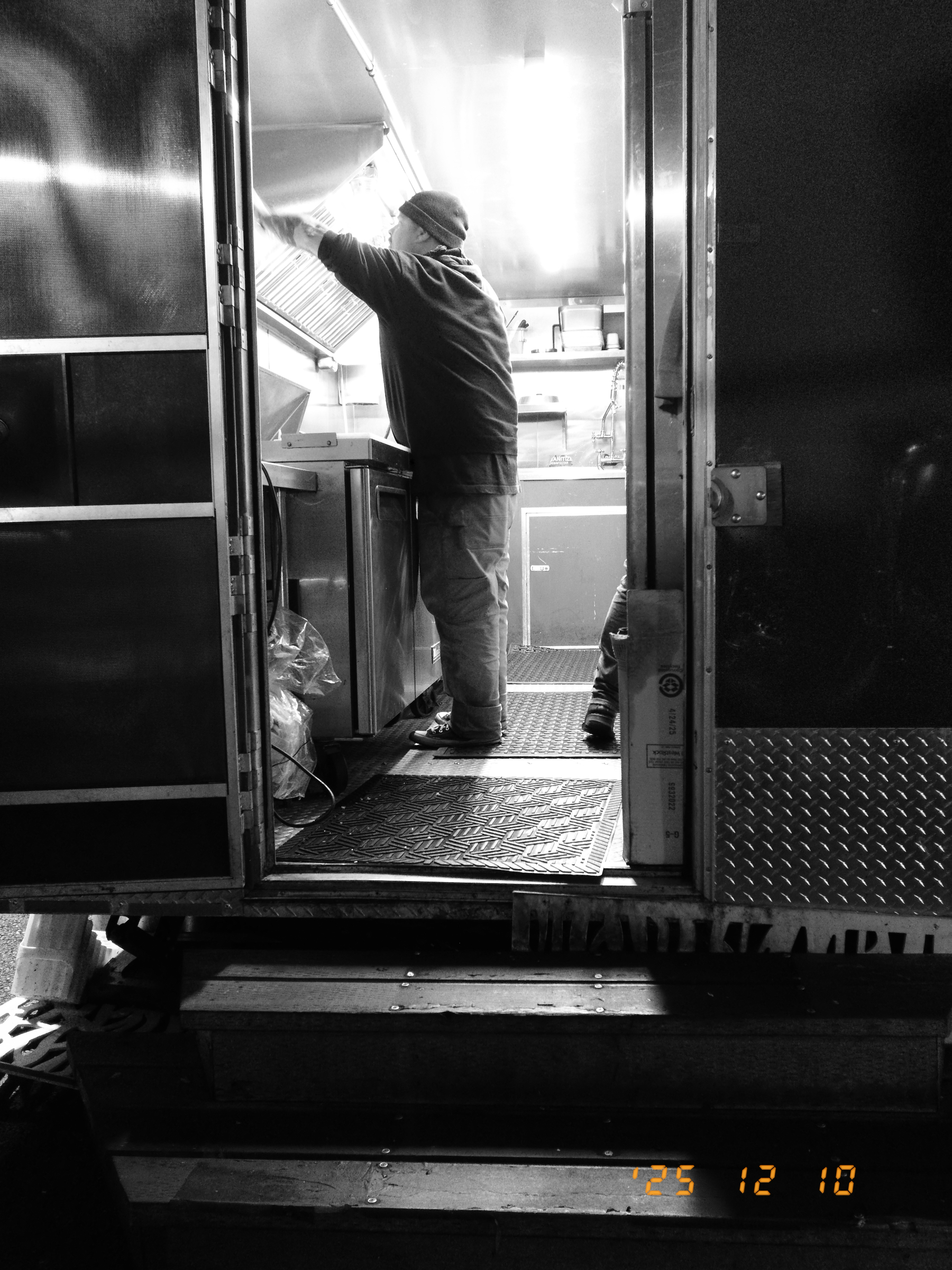 A person is working inside a food truck, as seen from the open side door.