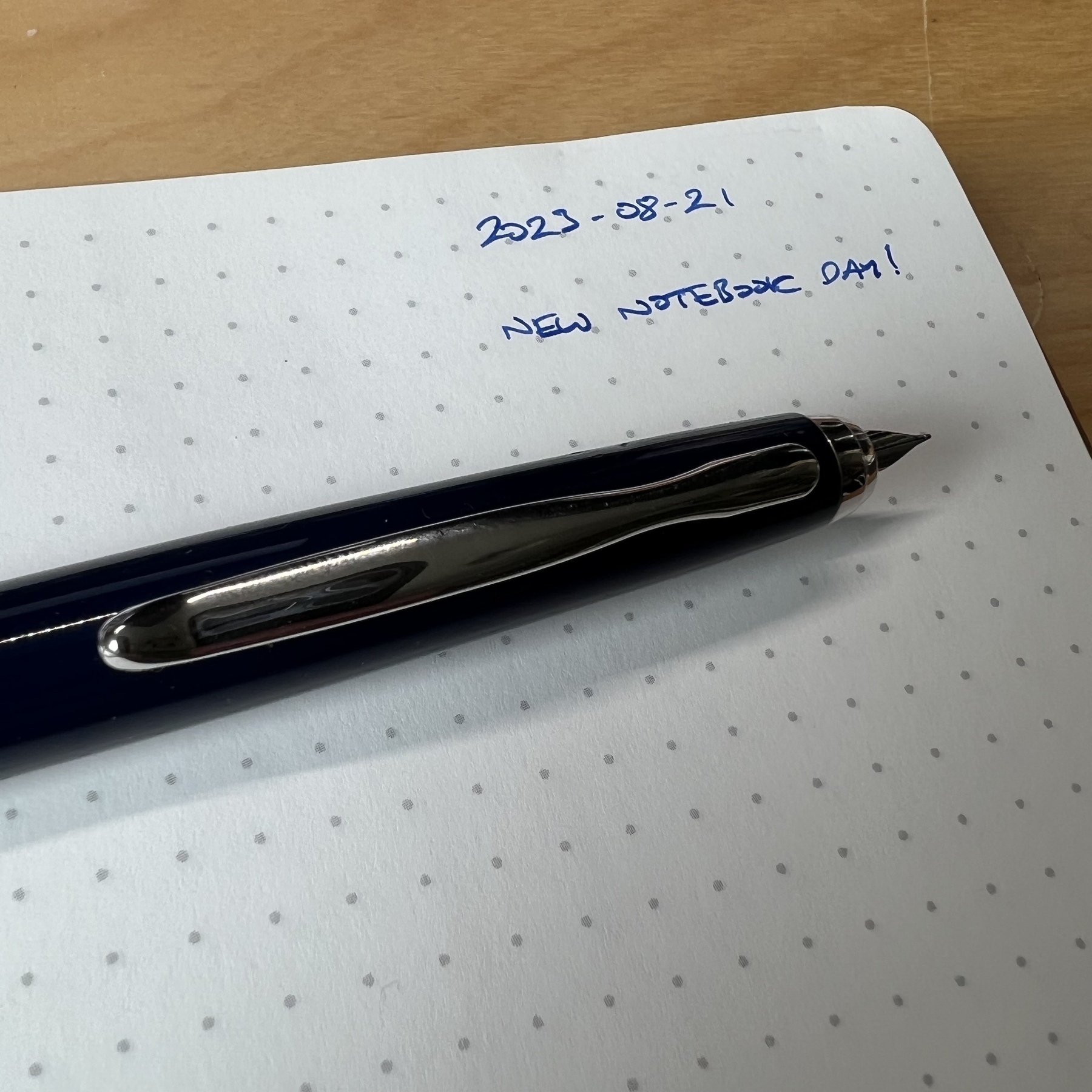 Photograph of a fountain pen sitting on a notebook page. Written on the page is today’s date and the words “New notebook day”.
