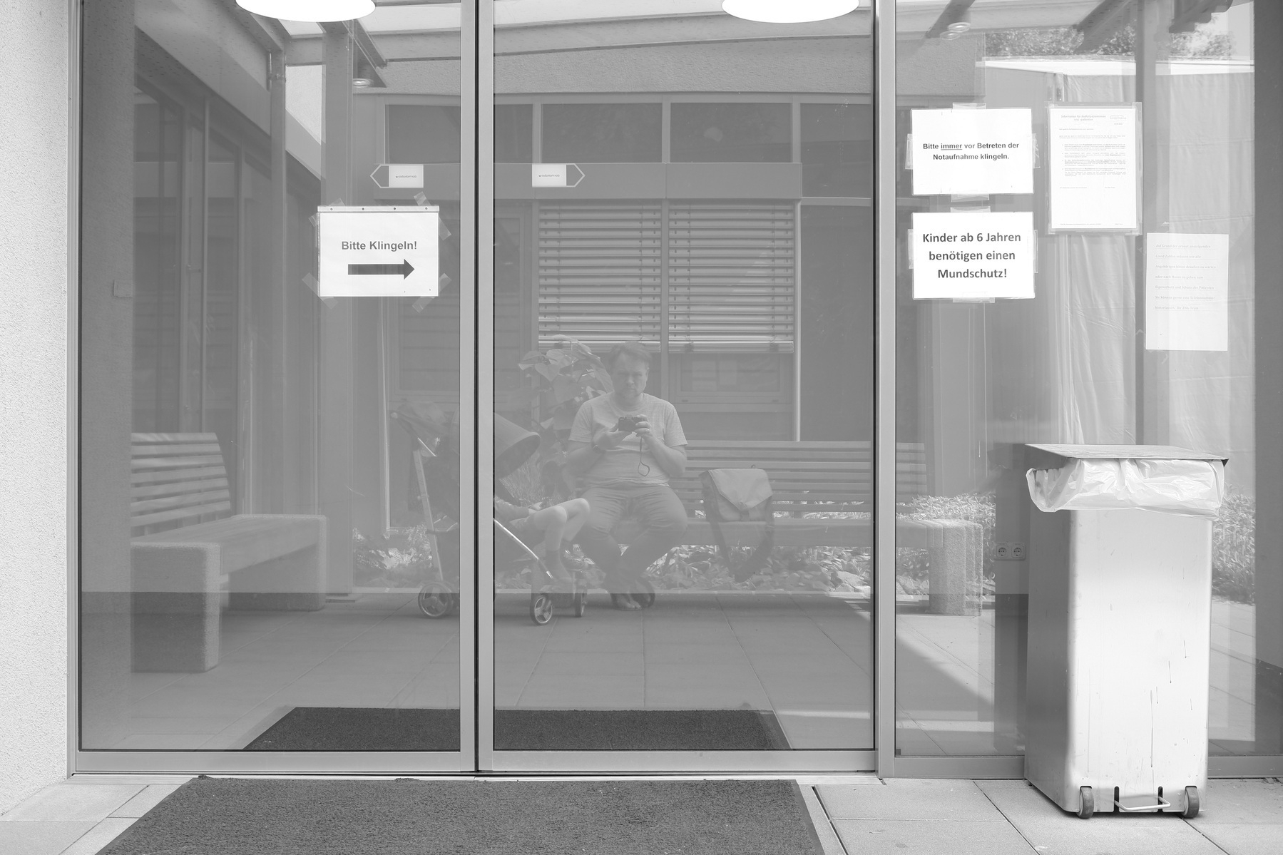 A photo of the reflection of my son in the buggy and me in front of the door of the emergency room.